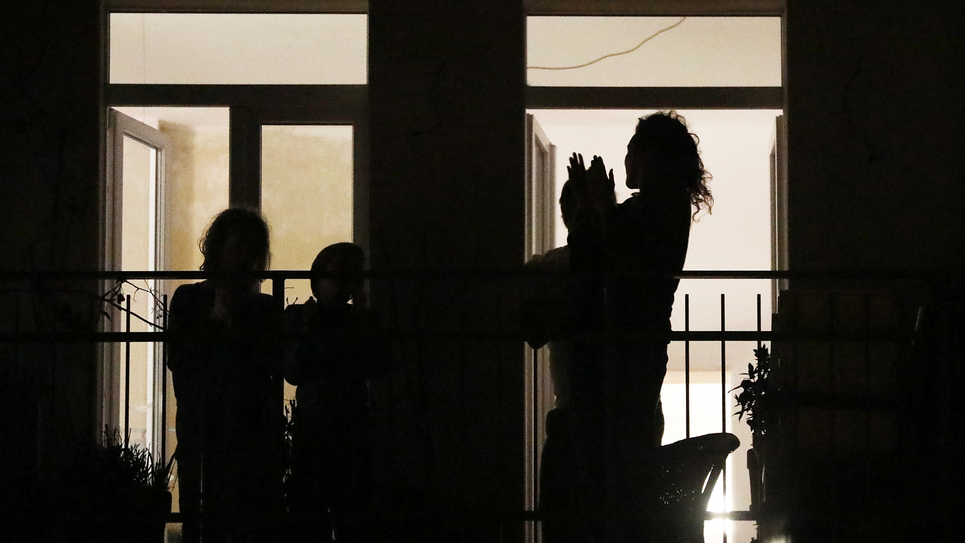 Menschen stehen im Dunkeln auf dem Balkon und klatschen. | Bildquelle: dpa