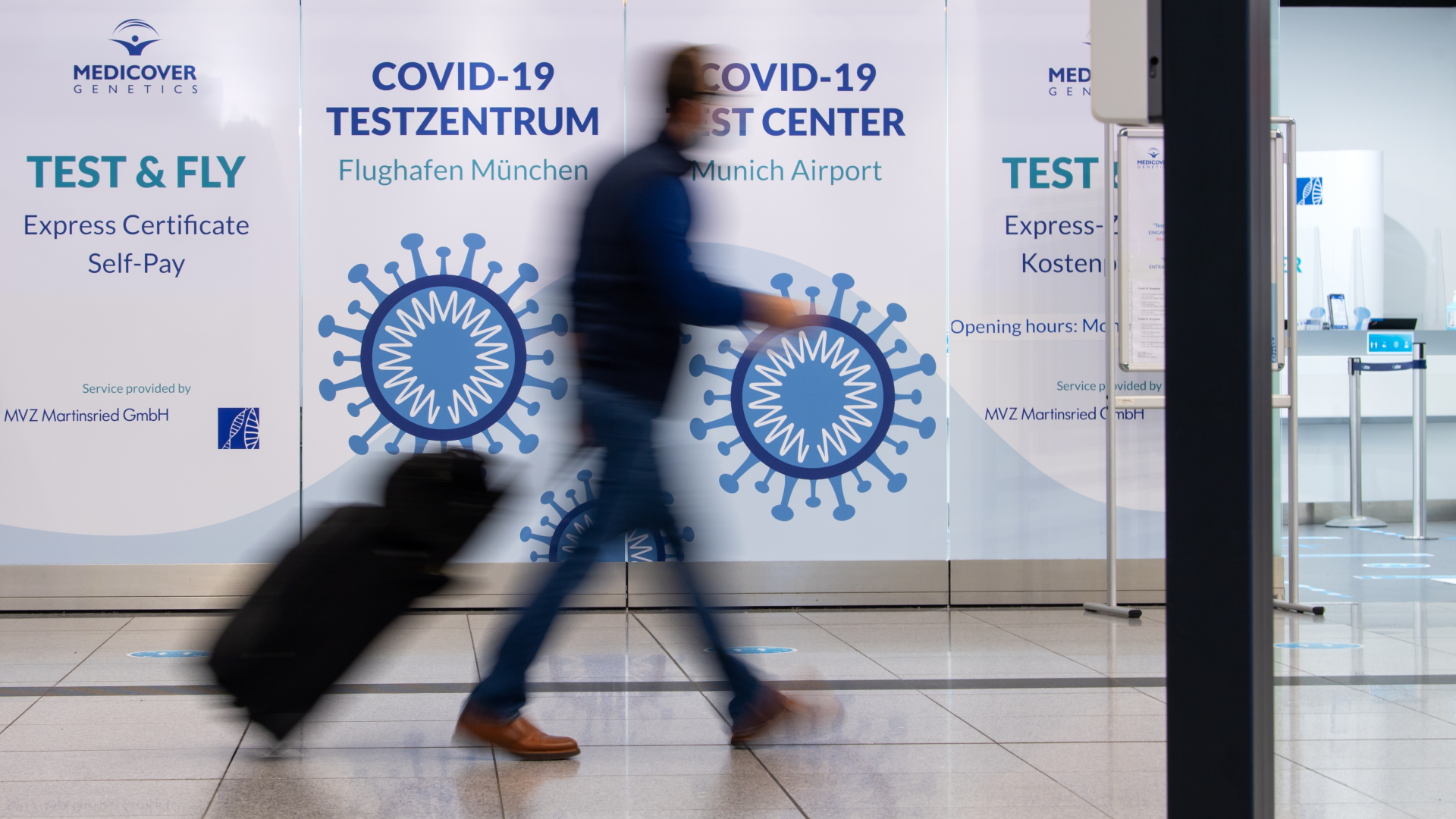 Ein Passagier geht am Flughafen München an einem Covid-19 Testzentrum vorbei. | dpa