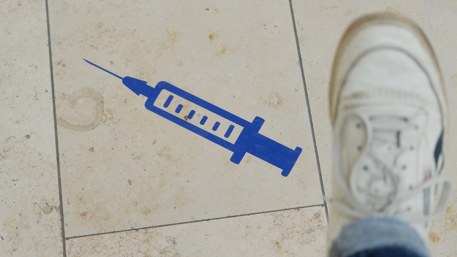 Eine Spritze ist auf den Boden eines Impfzentrums in Sachsen gemalt worden. | dpa