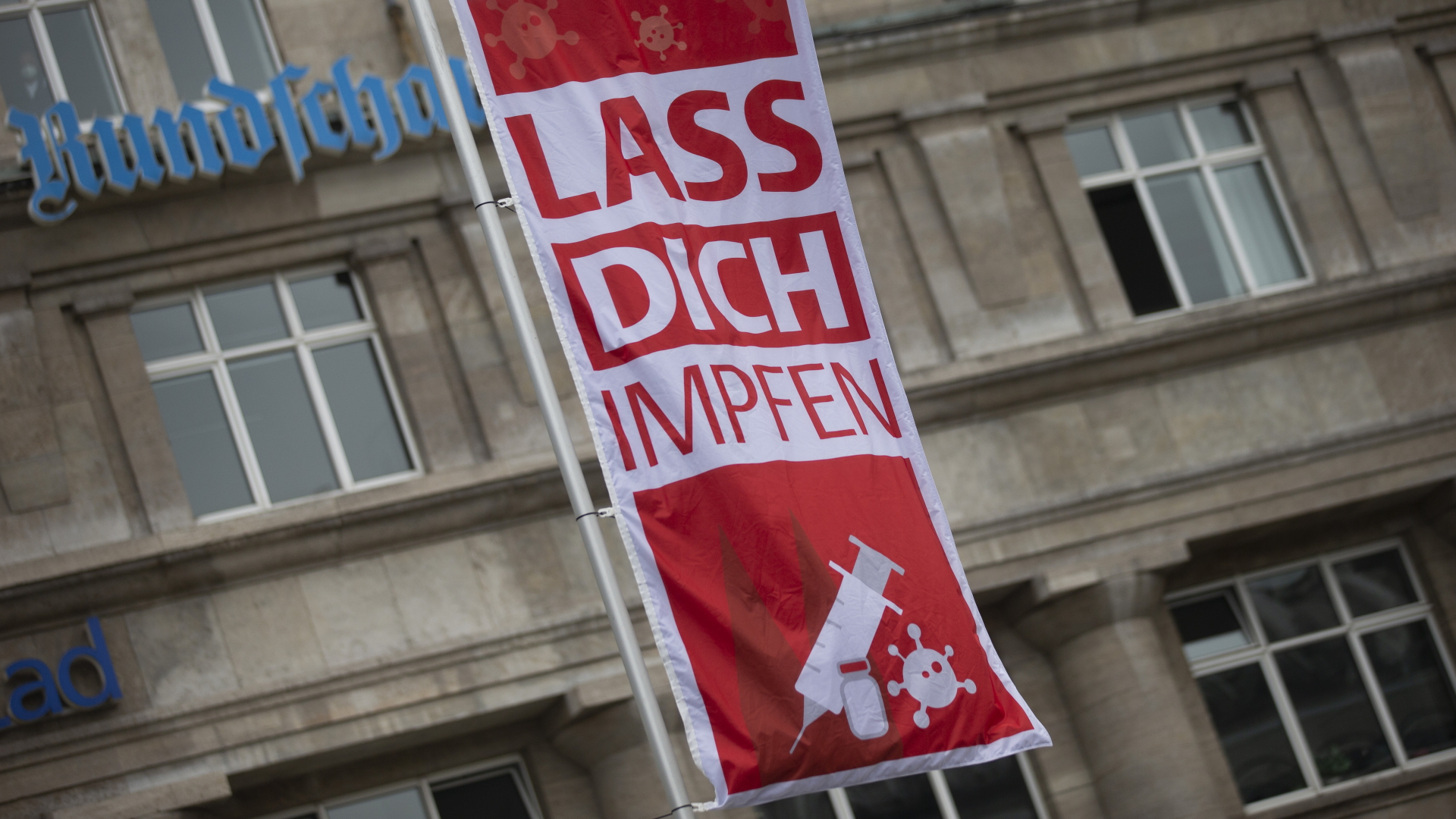 "Lass Dich impfen" steht auf einer Fahne während einer Corona-Impfaktion der Stadt Köln vor dem Hauptbahnhof