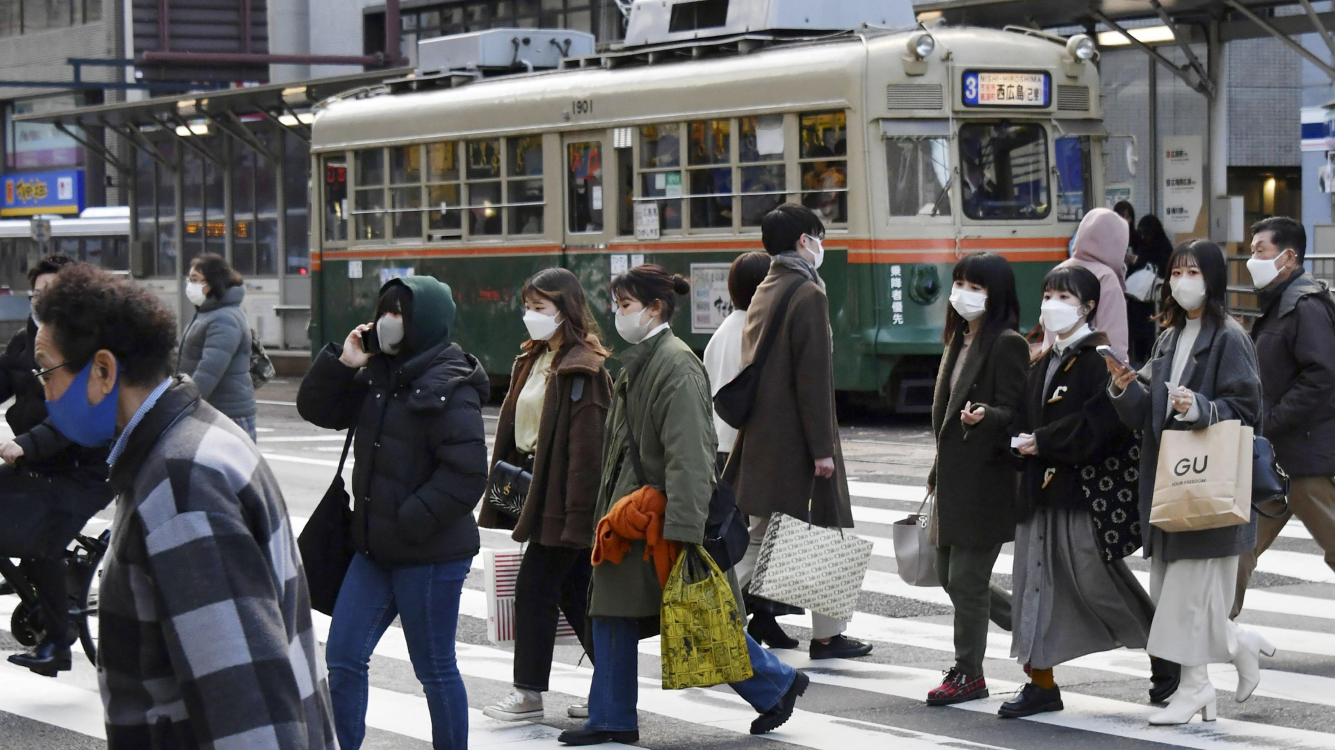 Passanten mit Schutzmasken überqueren eine Straße in der japanischen Stadt Hiroshima. | AP