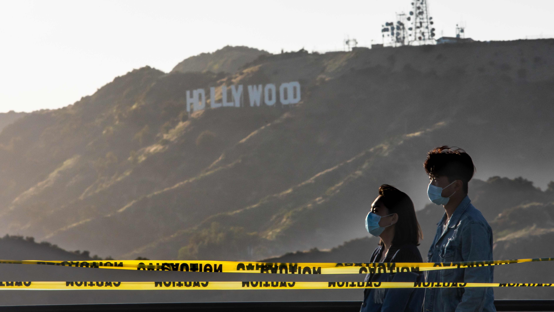 Das Hollywood-Logo und zwei Menschen mit Gesichtsmasken | AFP