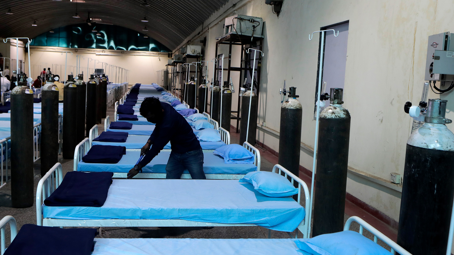 Ein Arbeiter reinigt die Betten in einem temporären Corona-Krankenhaus in Mumbai (Indien). | dpa
