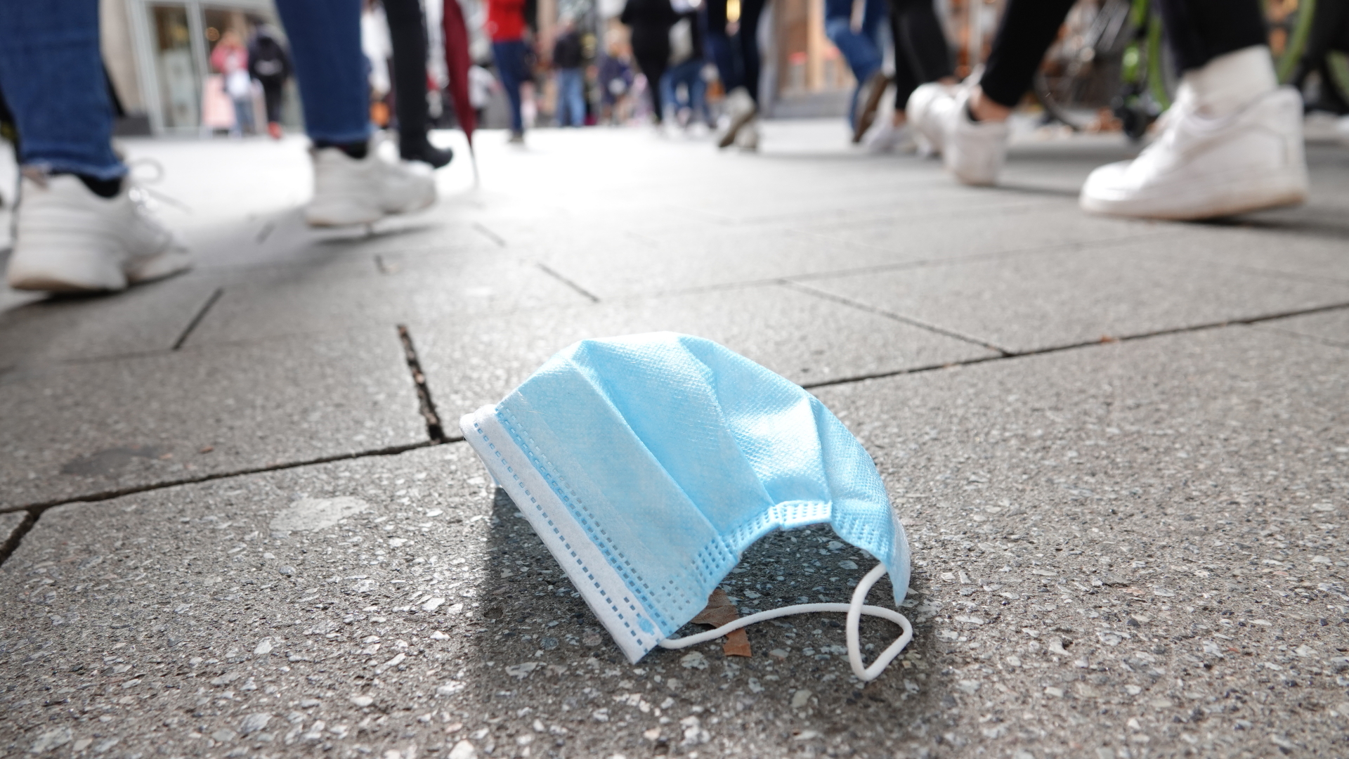 Ein Einwegmaske liegt in einer Fußgängerzone auf dem Boden | dpa