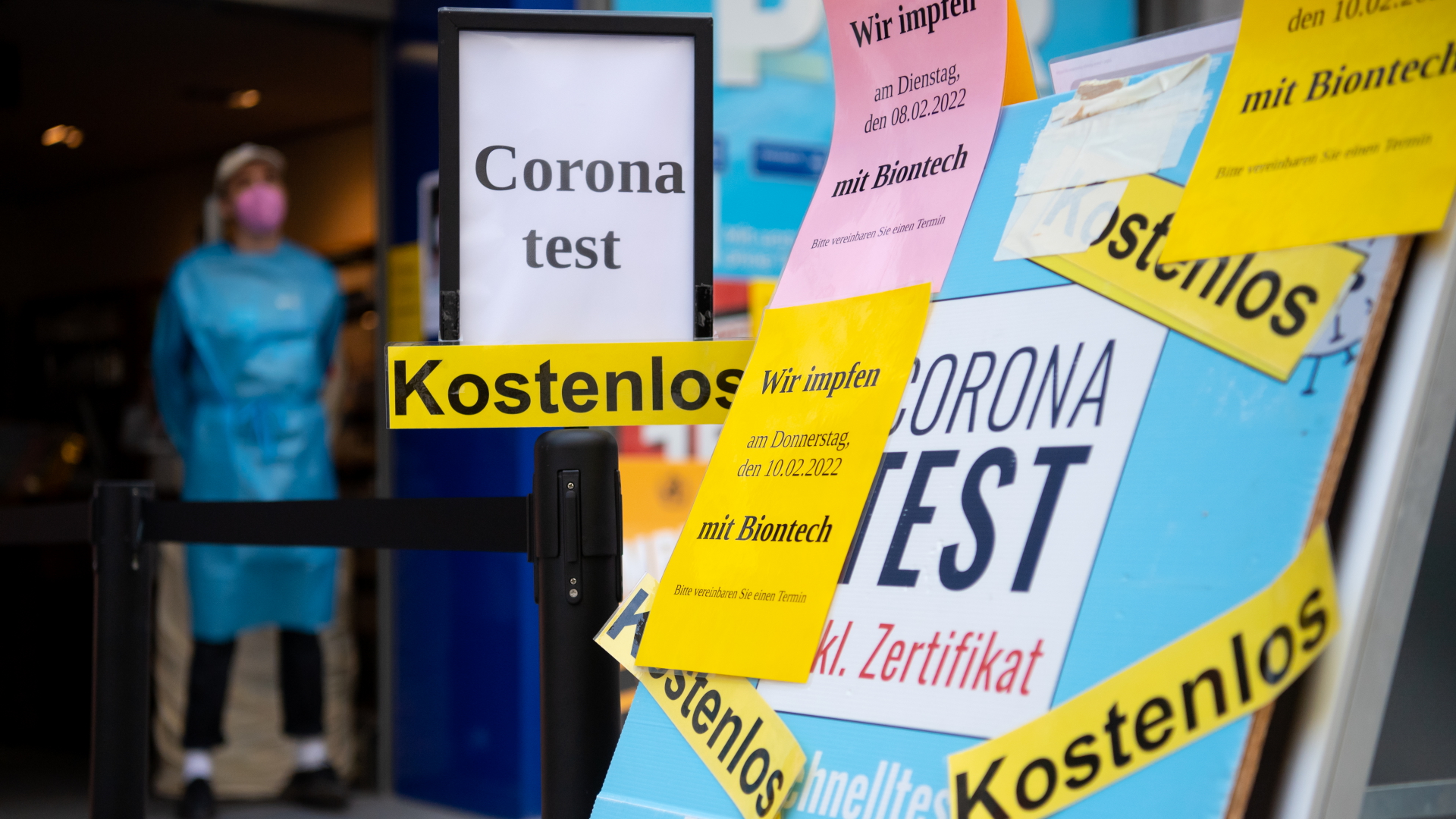 Ein Plakat mit Hinweisen auf Impftermine und kostenlose Corona-Tests vor einer Apotheke in München.