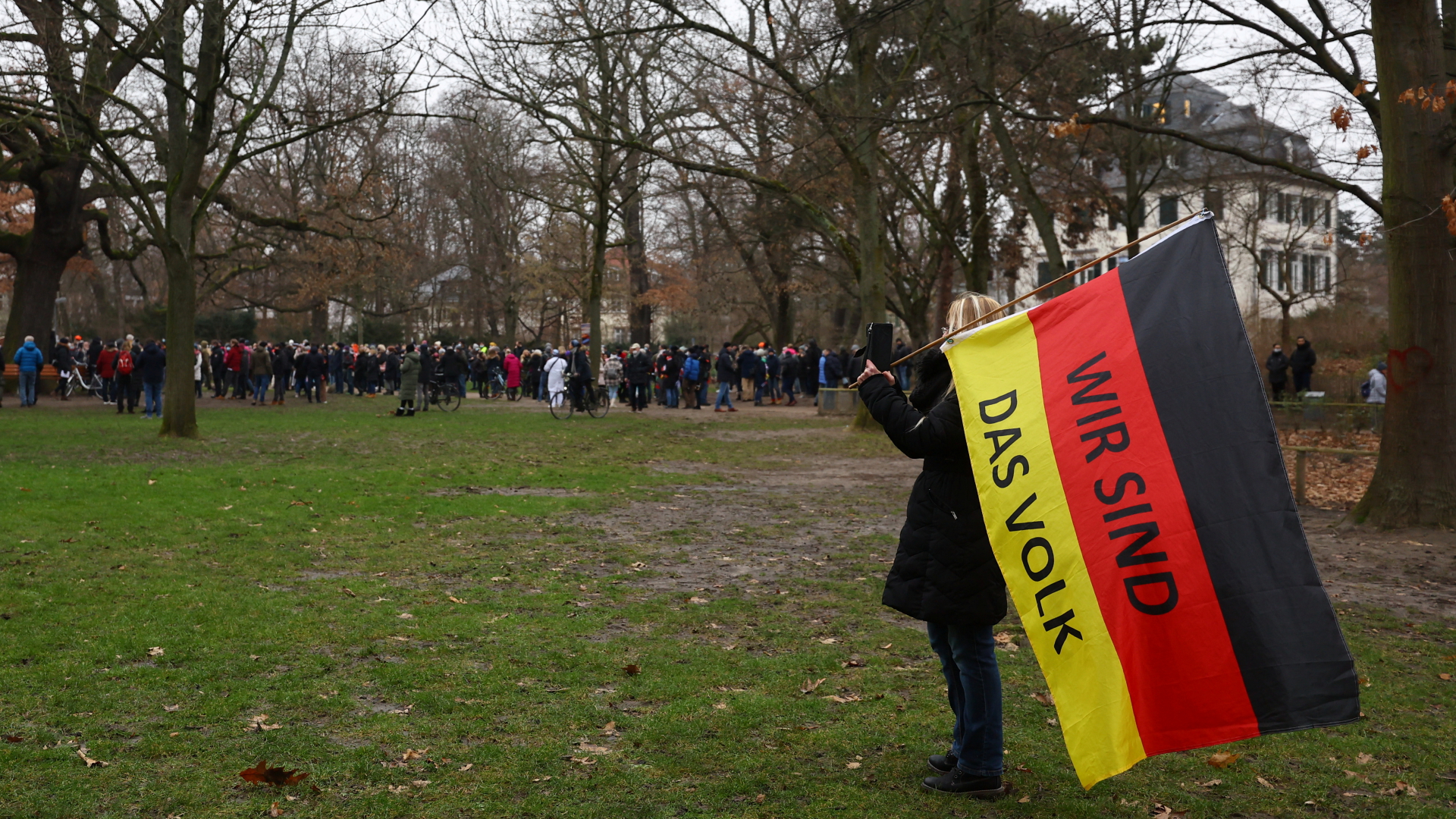 Eine Frau hält in Frankfurt am Main eine Deutschland-Flagge mit der Aufschrift "Wir sind das Volk" in der Hand. | REUTERS