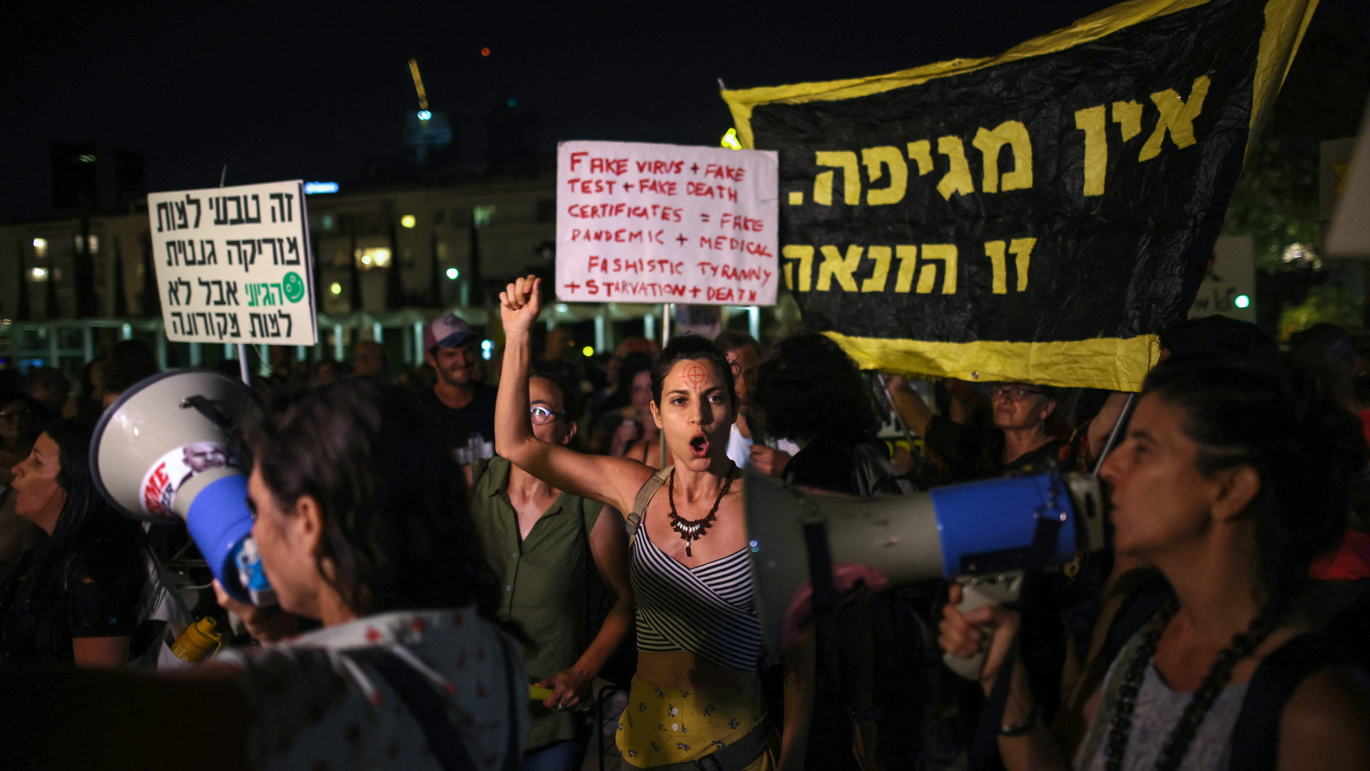Menschen in Tel Aviv protestieren mit Plakaten und Megaphonen gegen die Corona-Maßnahmen in Israel. | AFP