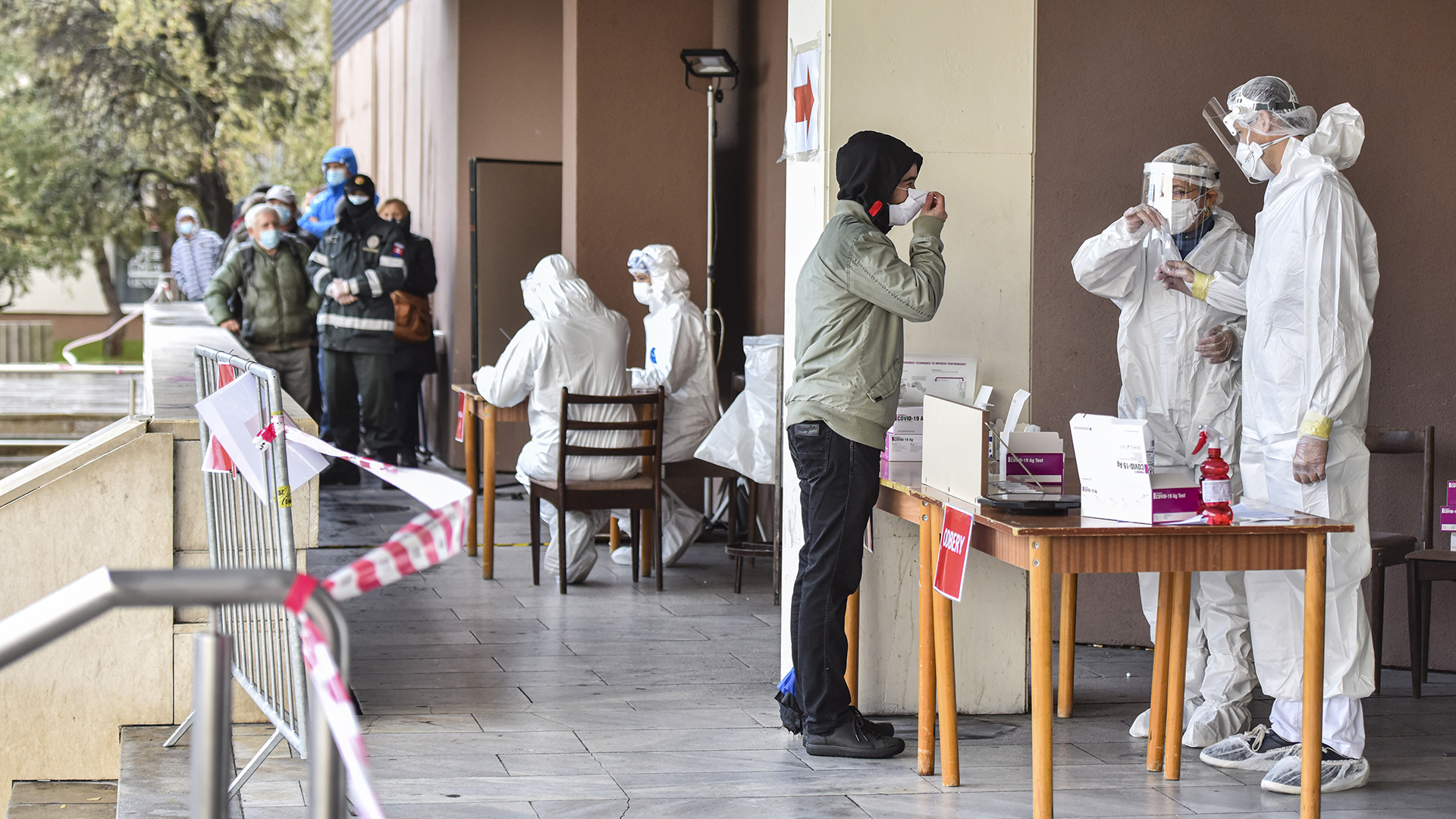 Eine Person macht einen Corona-Test, während im Hintergrund noch viele weitere in einer Schlange in Pezinok, Slowakei, warten. | dpa
