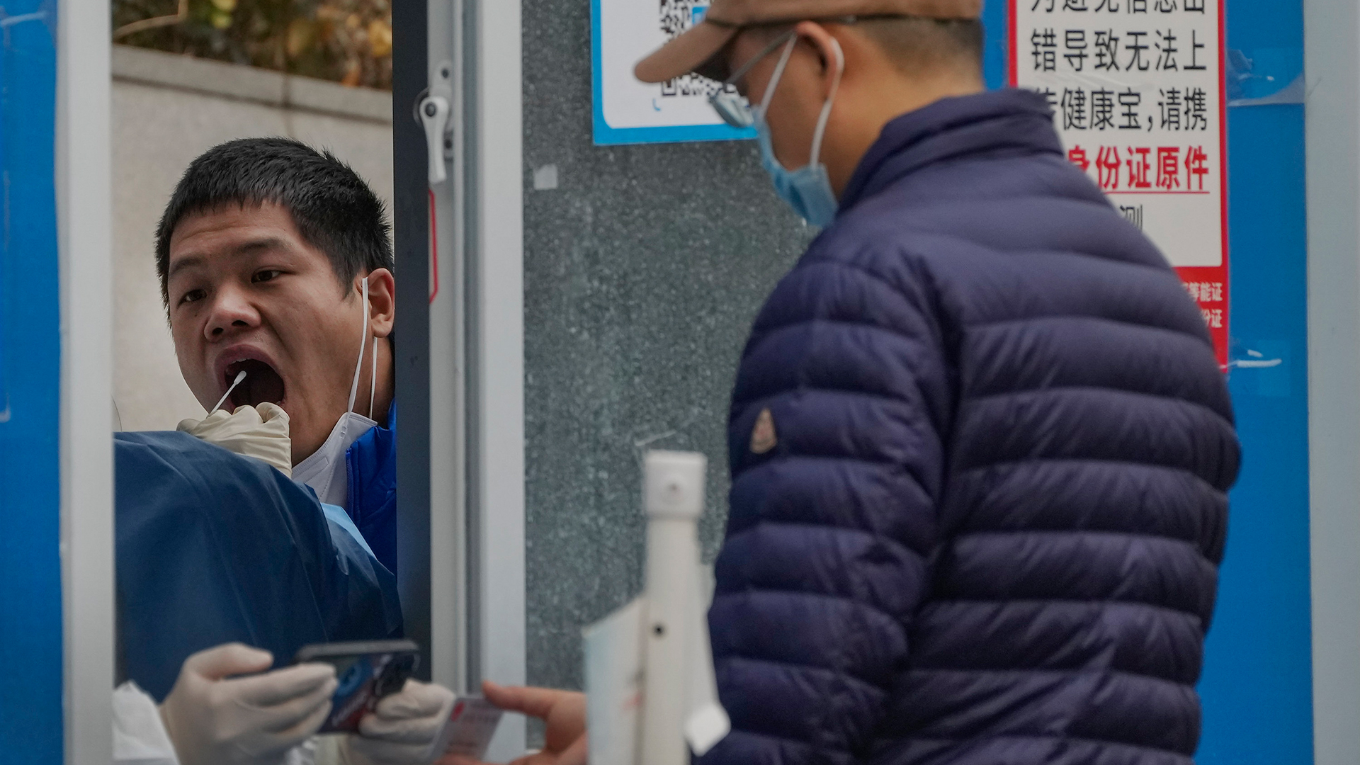 Ein Mann lässt sich in einem Coronavirus-Testzentrum in Peking (China) einen Rachenabstrich für einen COVID-19-Test machen. | AP