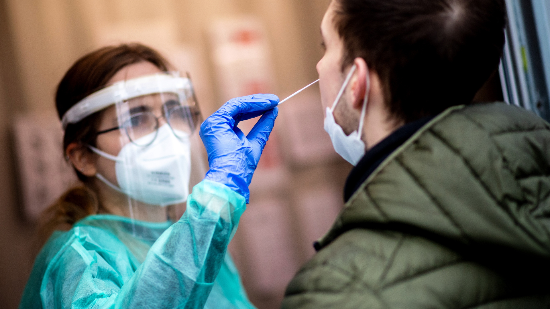 Eine Mitarbeiterin einer Teststation nimmt einen Nasenabstrich von einem jungen Mann in Oldenburg. | dpa