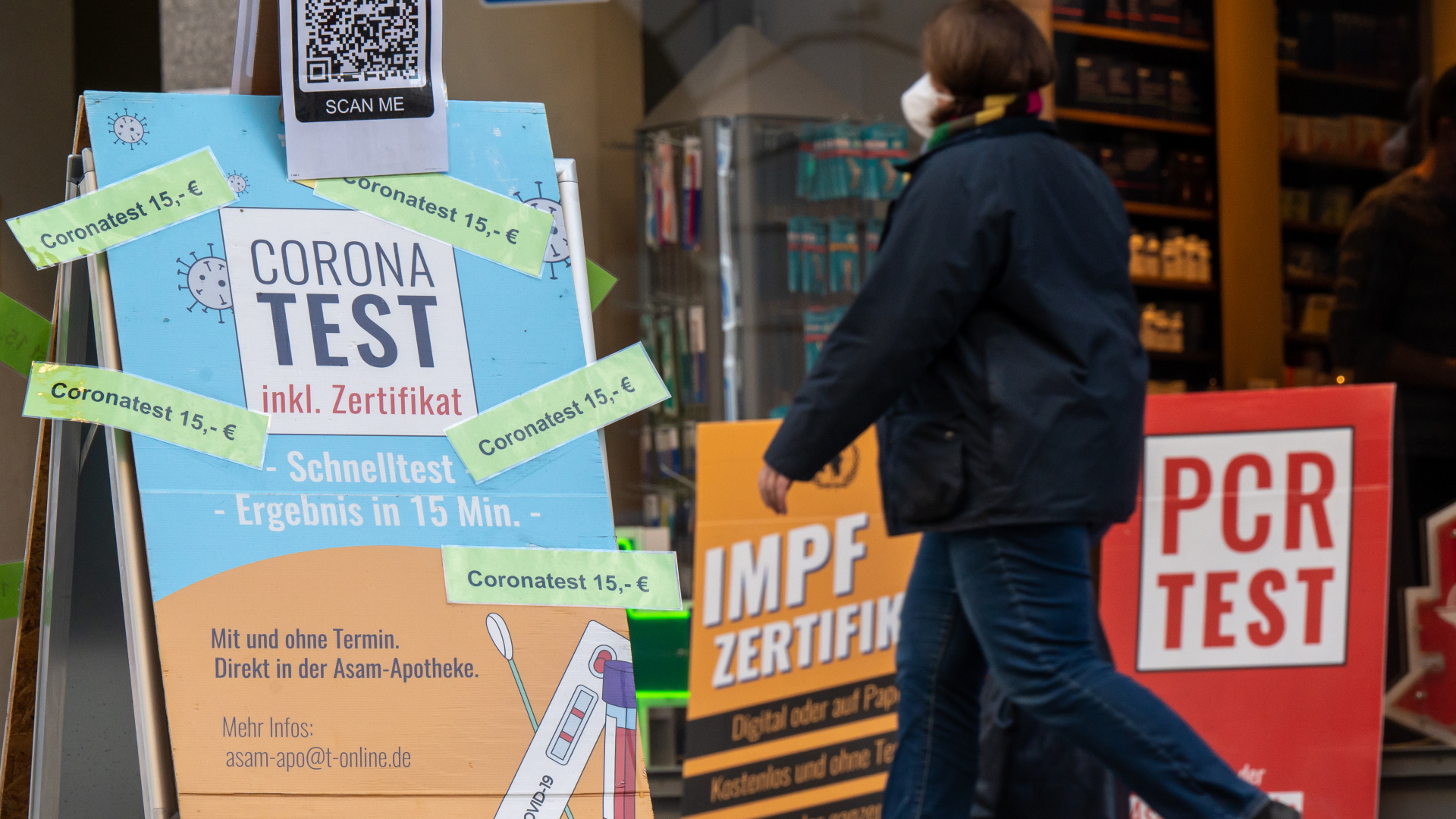 Eine Frau läuft in München Anfang November 2021 an einem Schild vorbei, dass für kostenpflichtige Corona-Tests wirbt. | dpa