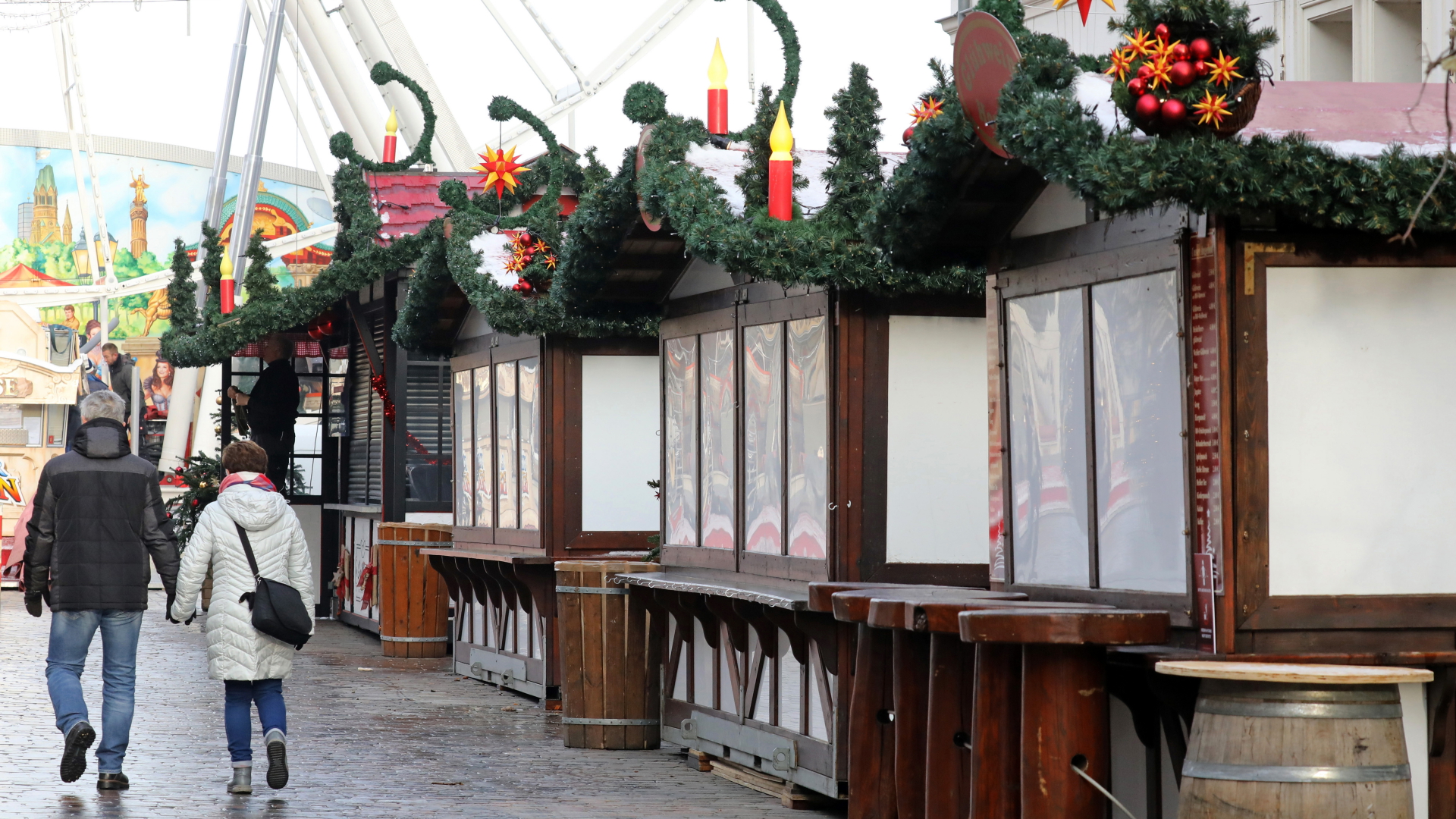 Passanten laufen an wegen der Corona-Pandemie geschlossenen Buden des Weihnachtsmarktes in der Schweriner Innenstadt vorbei. | dpa