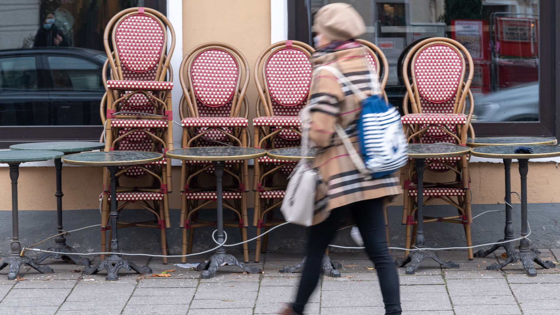 Eine Frau läuft Anfang Dezember 2020 an einem geschlossenen Café in München vorbei.