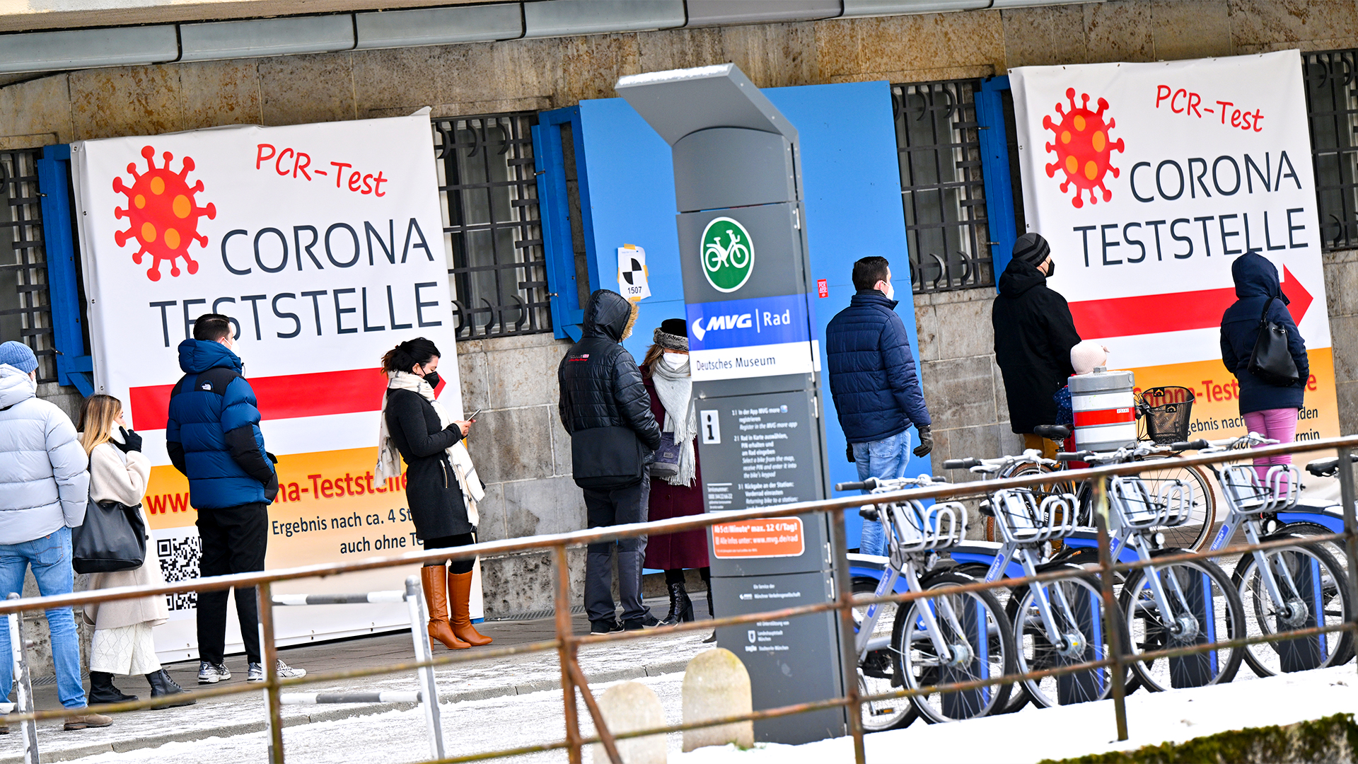 Passanten stehen vor einem Corona-Testzentrum in München an. | dpa