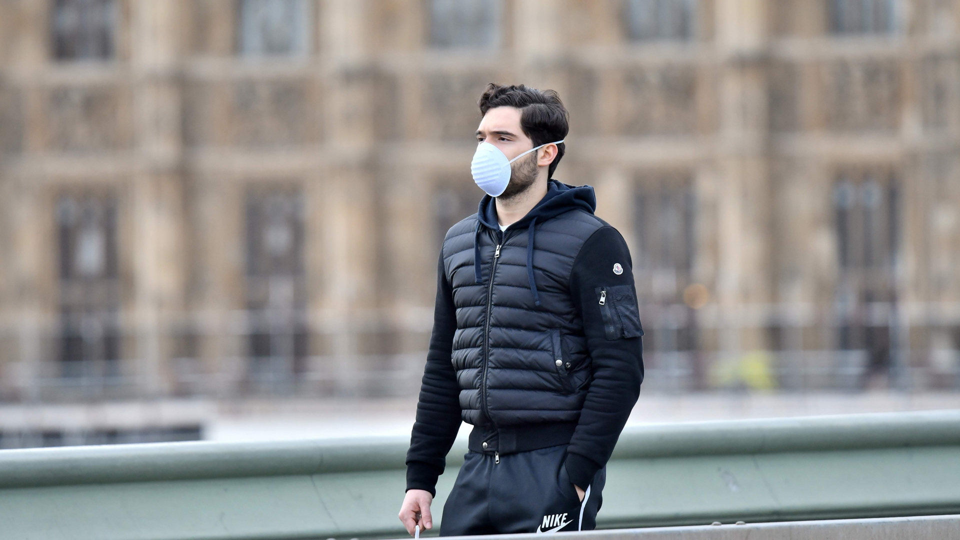 Ein Passant in London trägt einen Mundschutz | AFP