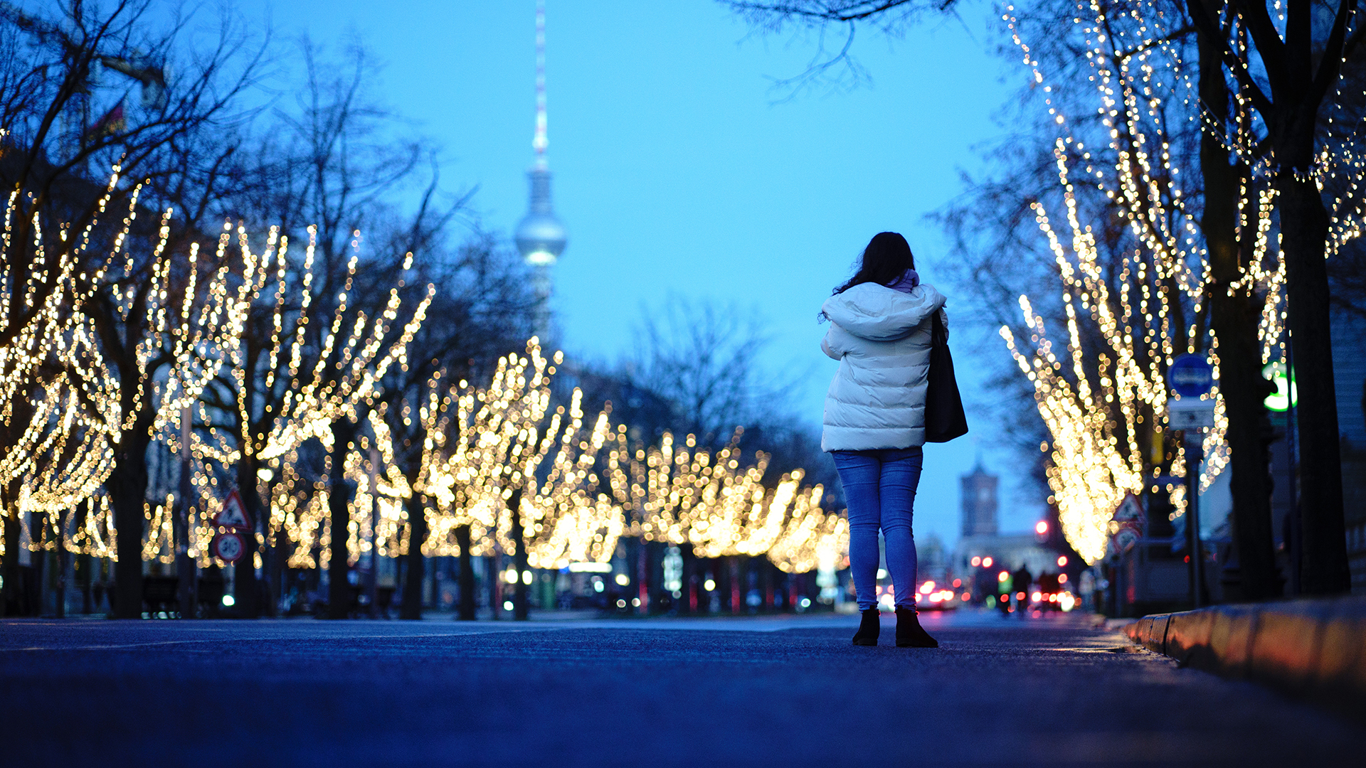 Eine Passantin fotografiert die weihnachtlich beleuchtete Straße Unter den Linden. 