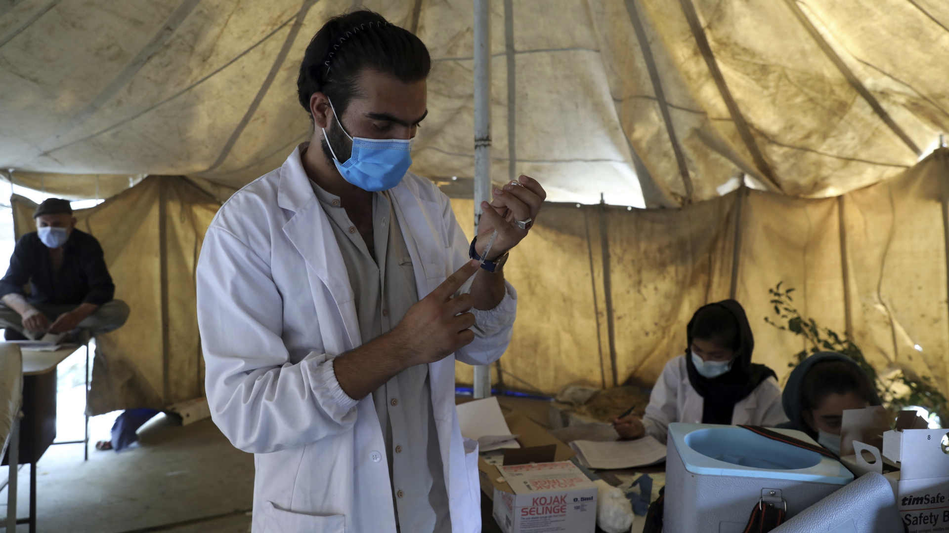 Ein Arzt zieht in einem Impfzentrum in Kabul eine Spritze mit Corona-Impfstoff auf. | AP
