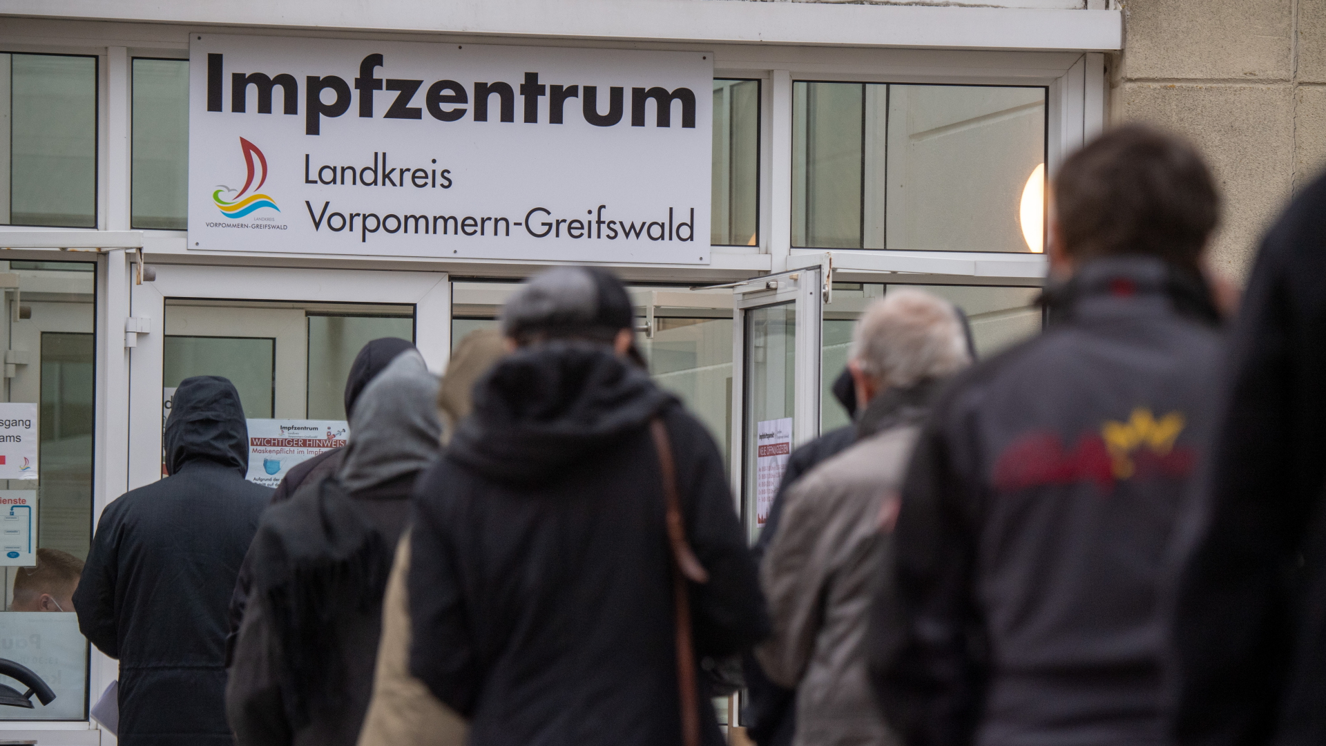 Ein Schild mit dem Schriftzug "Impfzentrum" weist den Weg zum Corona-Impfstützpunkt des Landkreis Vorpommern-Greifswald in Greifswald. | dpa