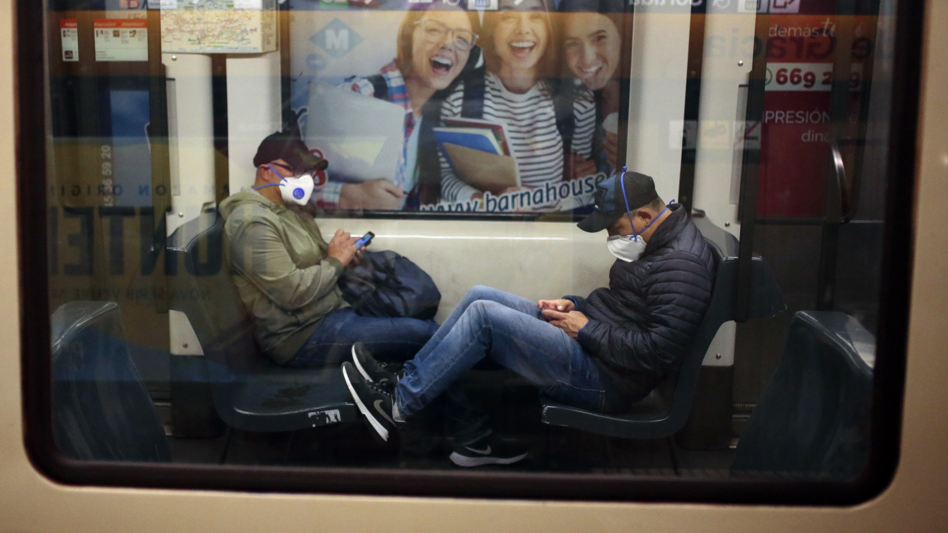 Zwei Passagiere mit Mundschutz sitzen in Barcelona in einem Zug.  | dpa