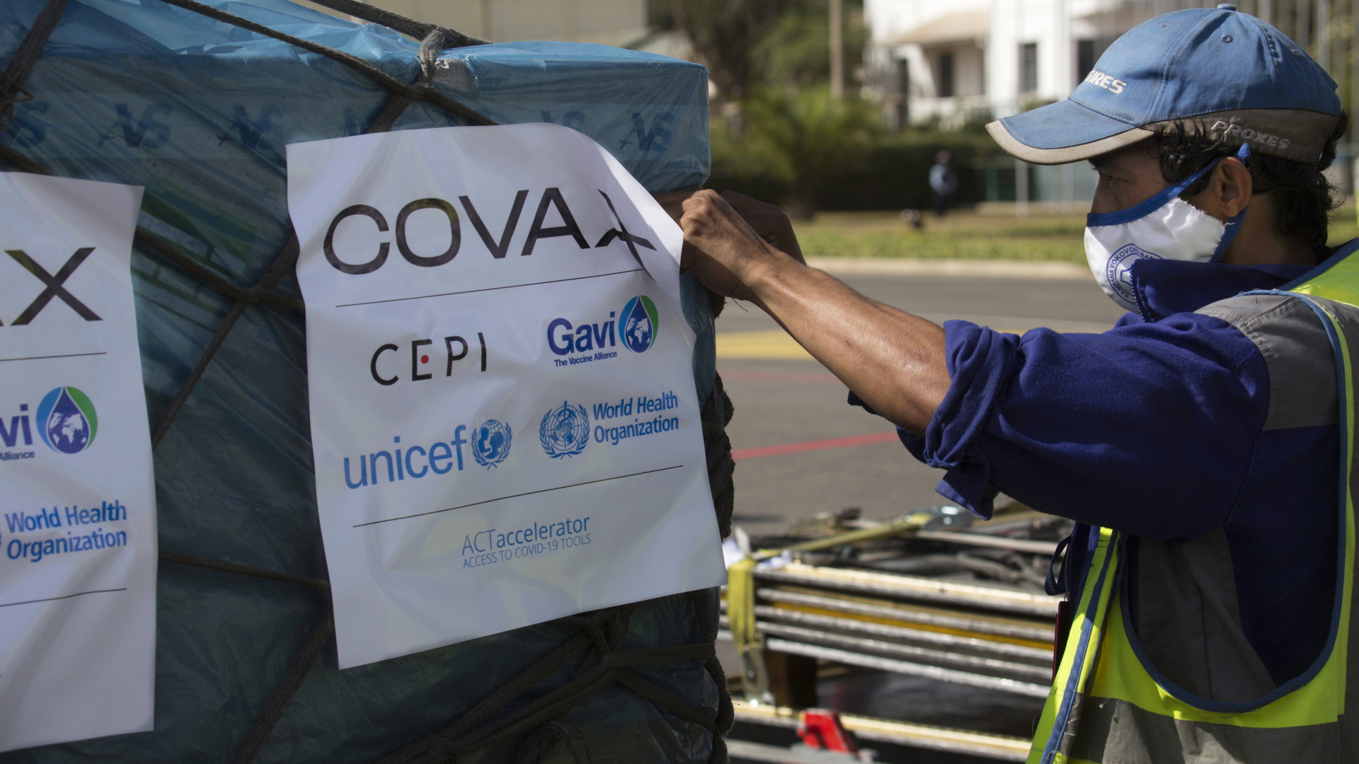 Ein Mitarbeiter mit Maske registriert eine verpackte Impfstoff-Lieferung von Covax. | AP