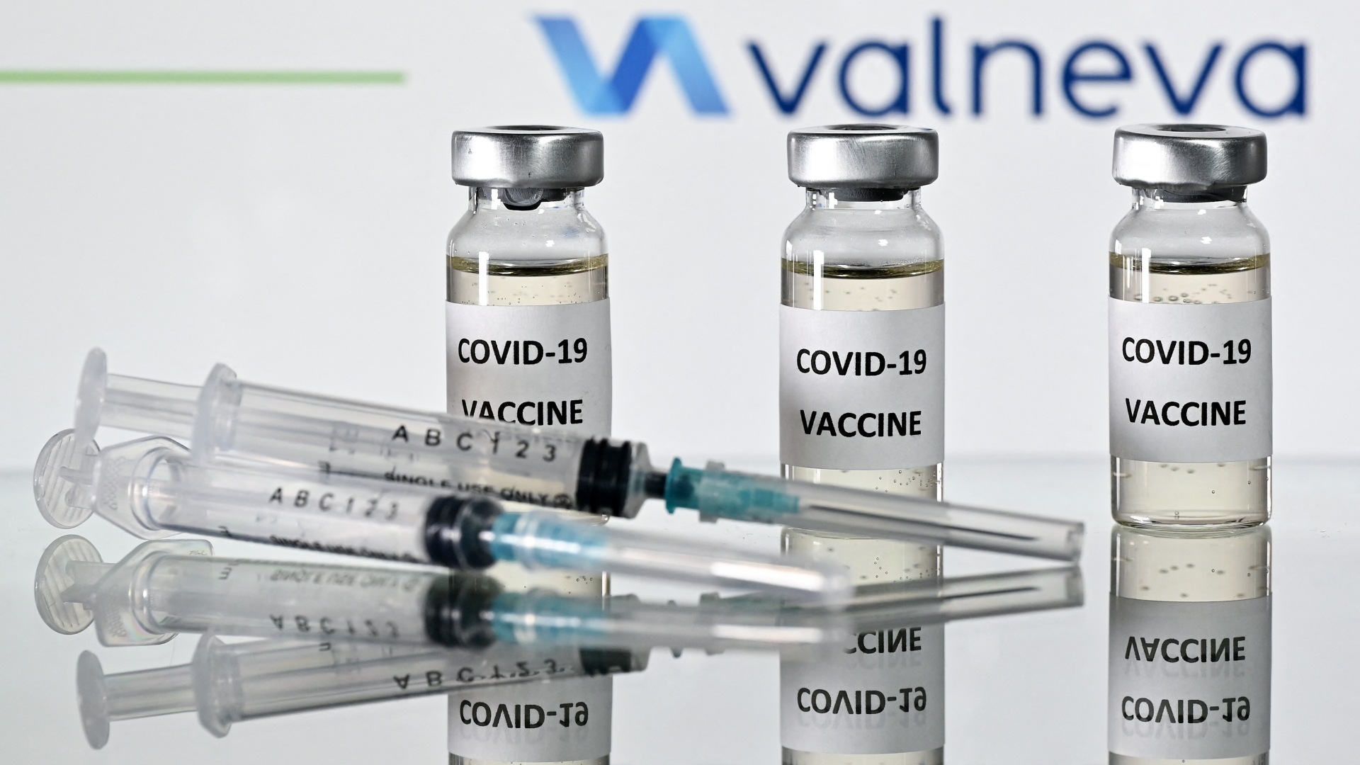 Drei Ampullen mit dem Corona-Impfstoff von Valneva liegen neben einer Spritze. | AFP
