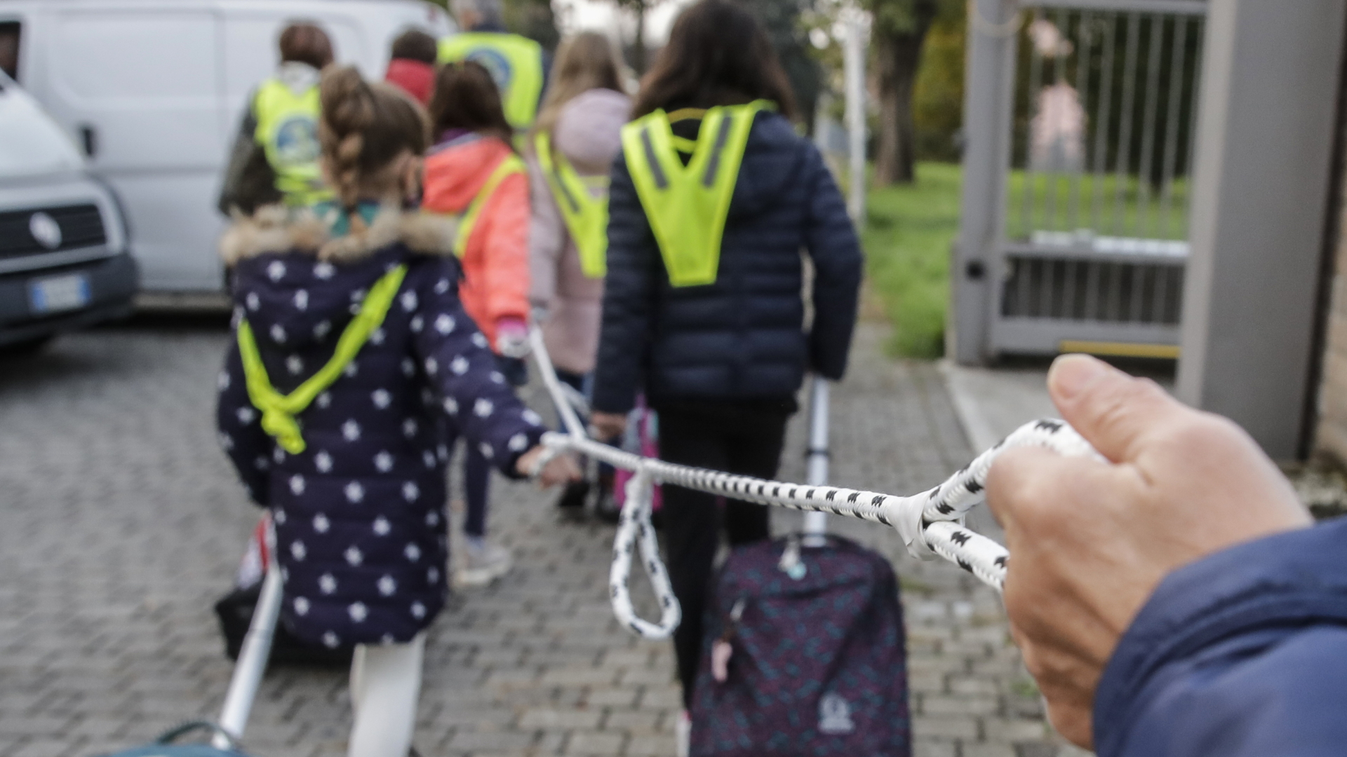 Schulkinder in Italien halten sich auf dem Weg in die Schule an einem Seil fest, in das Schlaufen geknotet wurden. Die sollen helfen, den in der Corona-Krise nötigen Mindestabstand einzuhalten. | dpa