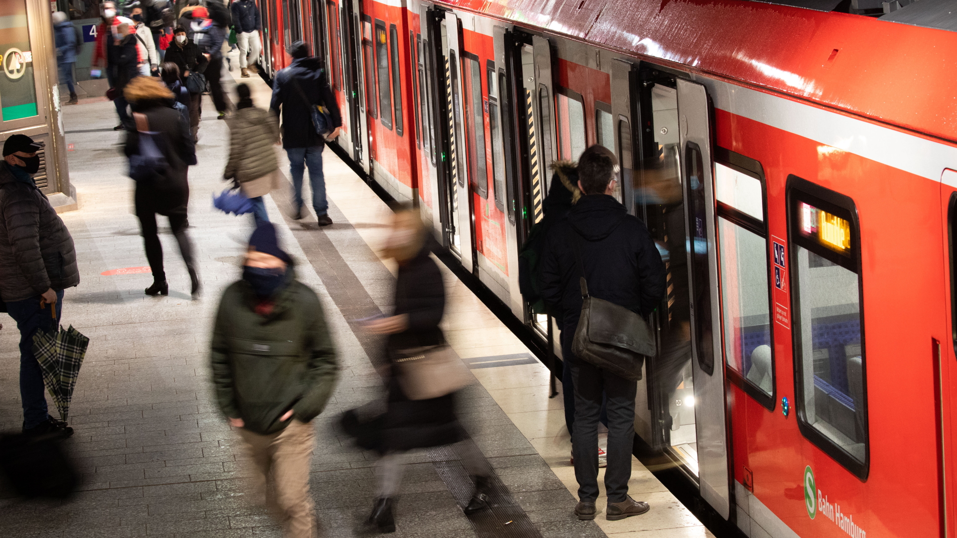 In Hamburg steigen Menschen mit Schutzmasken aus und in eine S-Bahn. | dpa
