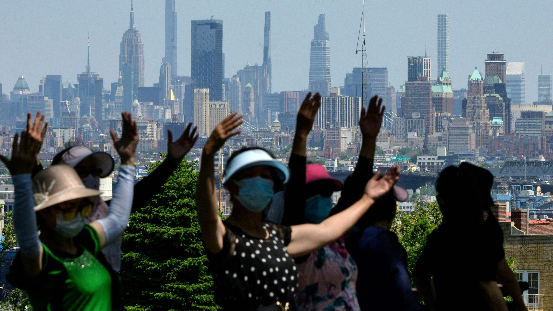 Frauen tanzen mit Corona-Masken vor der Skyline von New York. | AFP