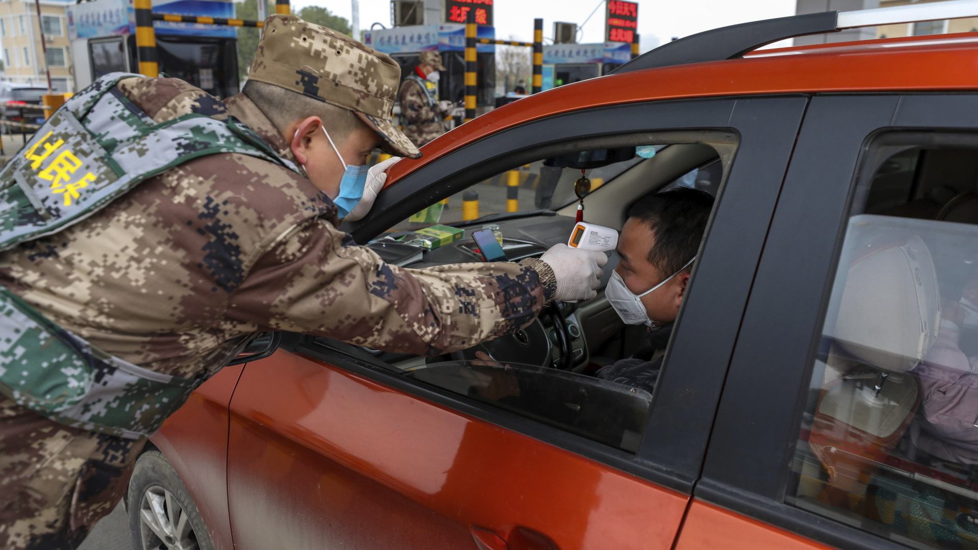 Ein Soldat des chinesischen Militärs führt nahe der Satdt Wuhan bei einem Autofahrer per Scanner eine Fieberkontrolle durch. | AP