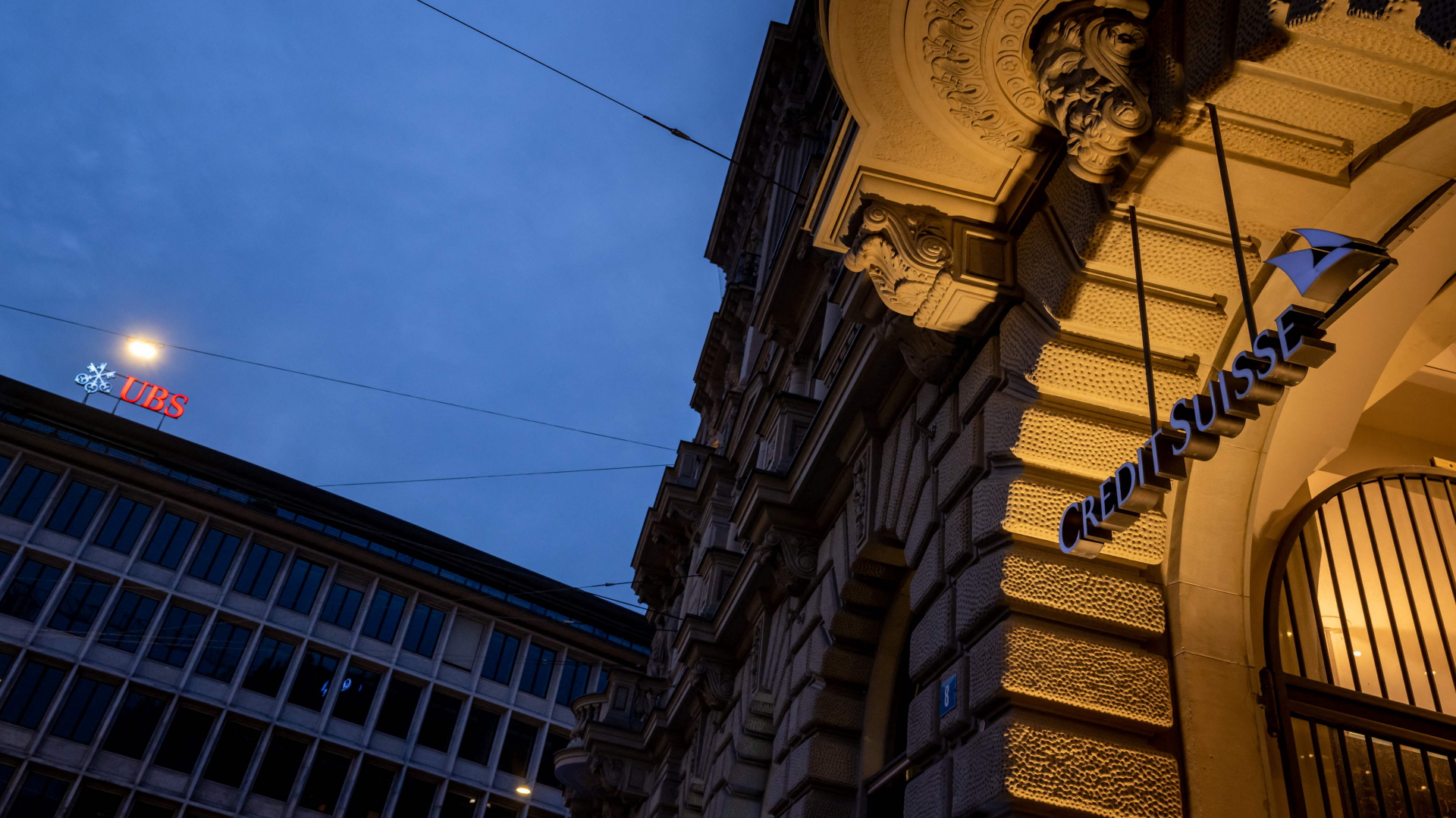 Die Gebäude der Credit Suisse und der UBS bei Nacht. | Foto: Fabrice COFFRINI / AFP