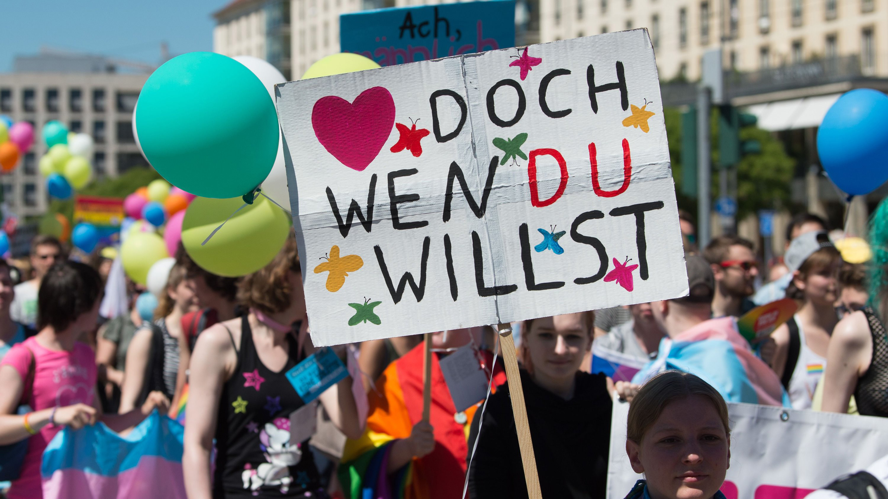 Beim CSD Ende Mai in Dresden ist ein Plakat mit der Aufschrift "Lieb' doch, wen du willst" zu sehen. | dpa