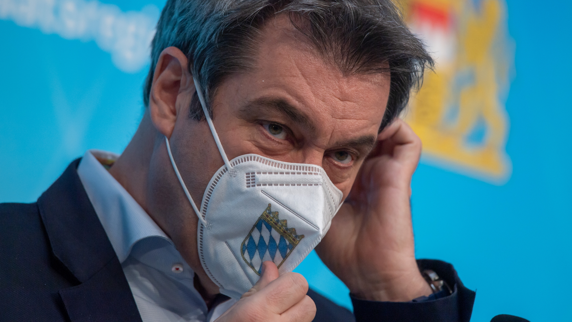 Bayerns Ministerpräsident Söder rückt eine FFP2-Maske mit dem Wappen seines Bundeslandes zurecht. | dpa