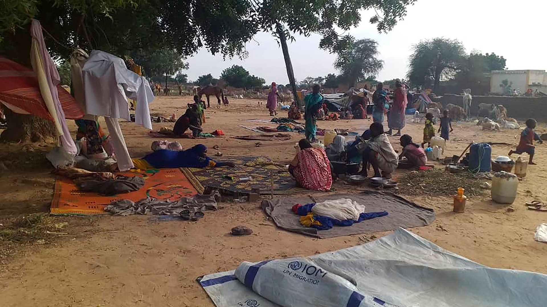 Vertriebene sitzen auf Decken inmitten provisorischer Zelte in dem Dorf Masteri.