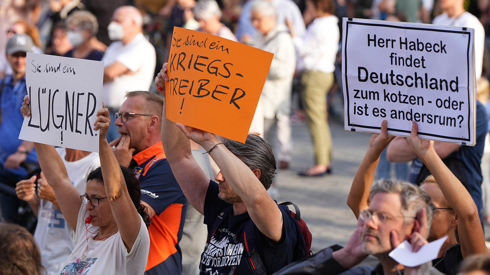 Demonstrierende halten während des Bürgerdialogs von Bundeswirtschaftsminister Habeck Plakate hoch. | dpa