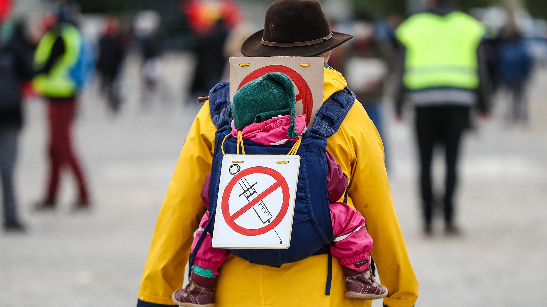 Eine Teilnehmerin einer Protestkundgebung der Initiative "Querdenker" trägt auf dem Cannstatter Wasen ein Schild gegen Impfungen auf ihrem Rücken. | dpa