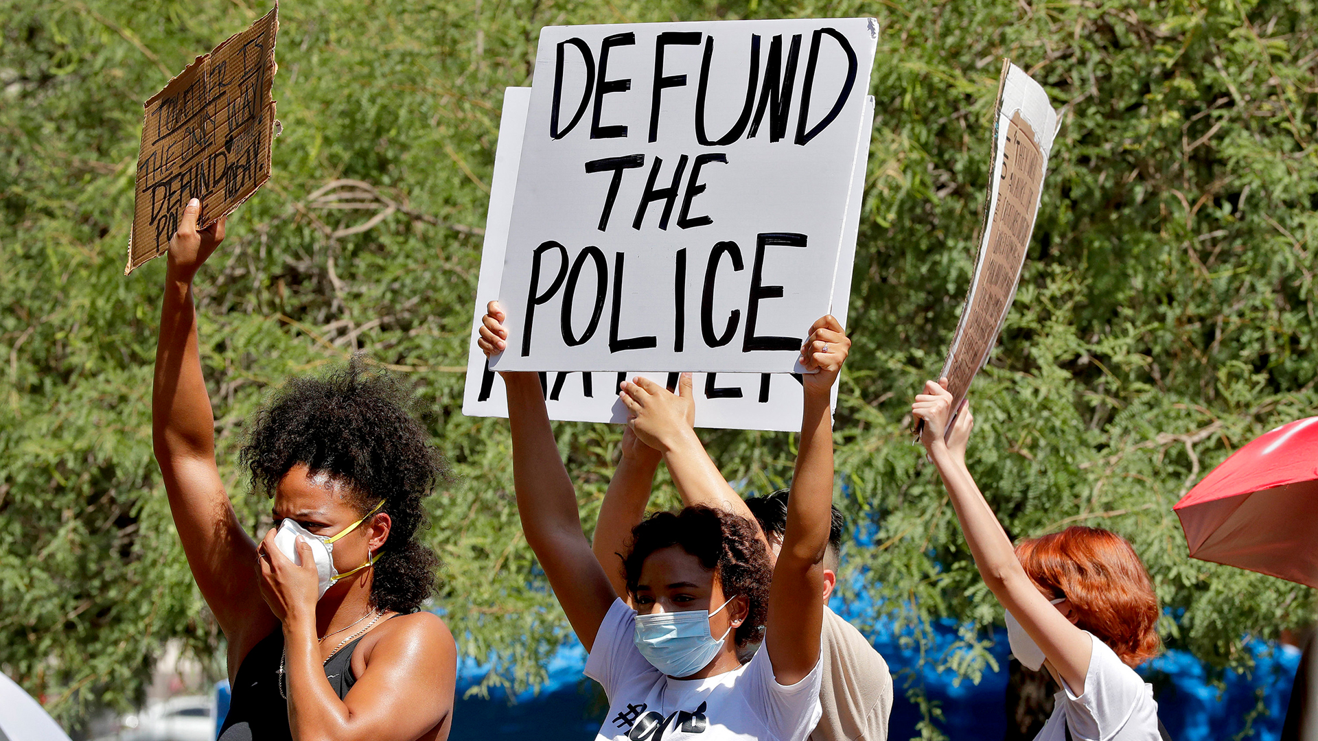 Demonstranten halten ein Schild mit der Aufschrift "Defund the Police" in den Händen | AP