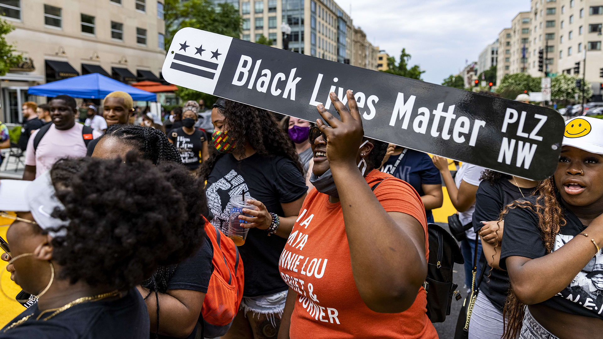 Eine Frau hält ein "Black Lives Matter Plaza"-Straßenschild in Washington, DC in die Höhe. | AFP