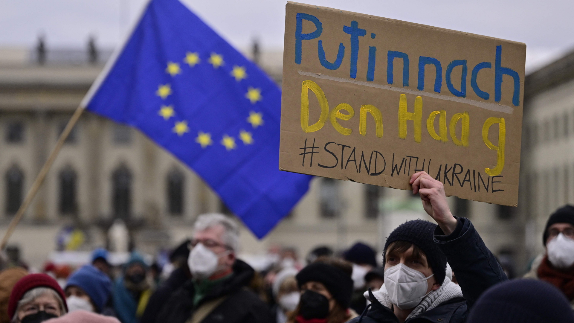 Ein Demonstrant fordert auf einer Kundgebung in Berlin am 6.3.2022 die Überstellung Putins nach Den Haag | AFP