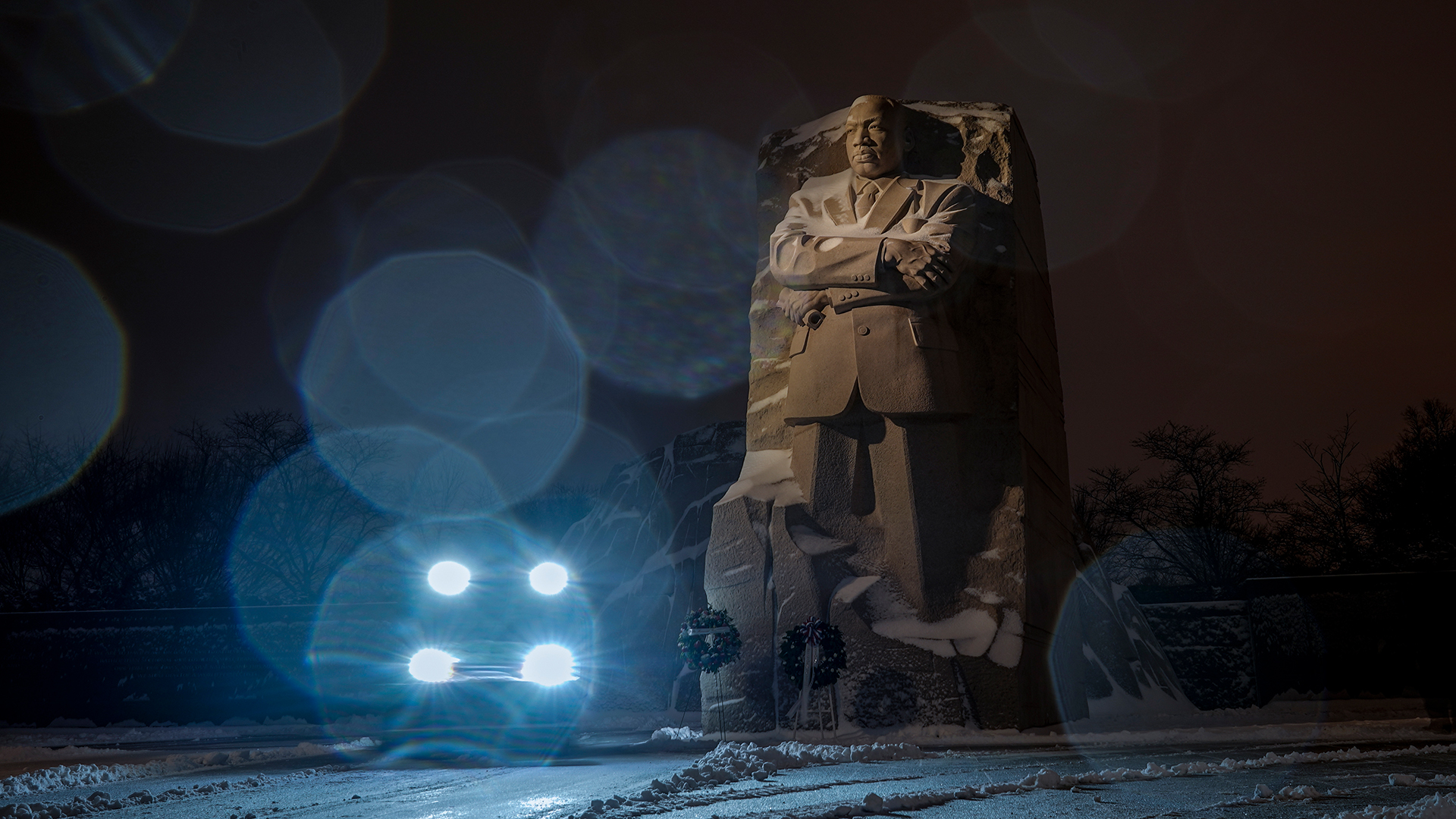 In einer Langzeitbelichtung beleuchten die Lichter eines Schneepfluges den Schneeregen am Martin-Luther-King-Nationaldenkmal in Washington (USA). | dpa