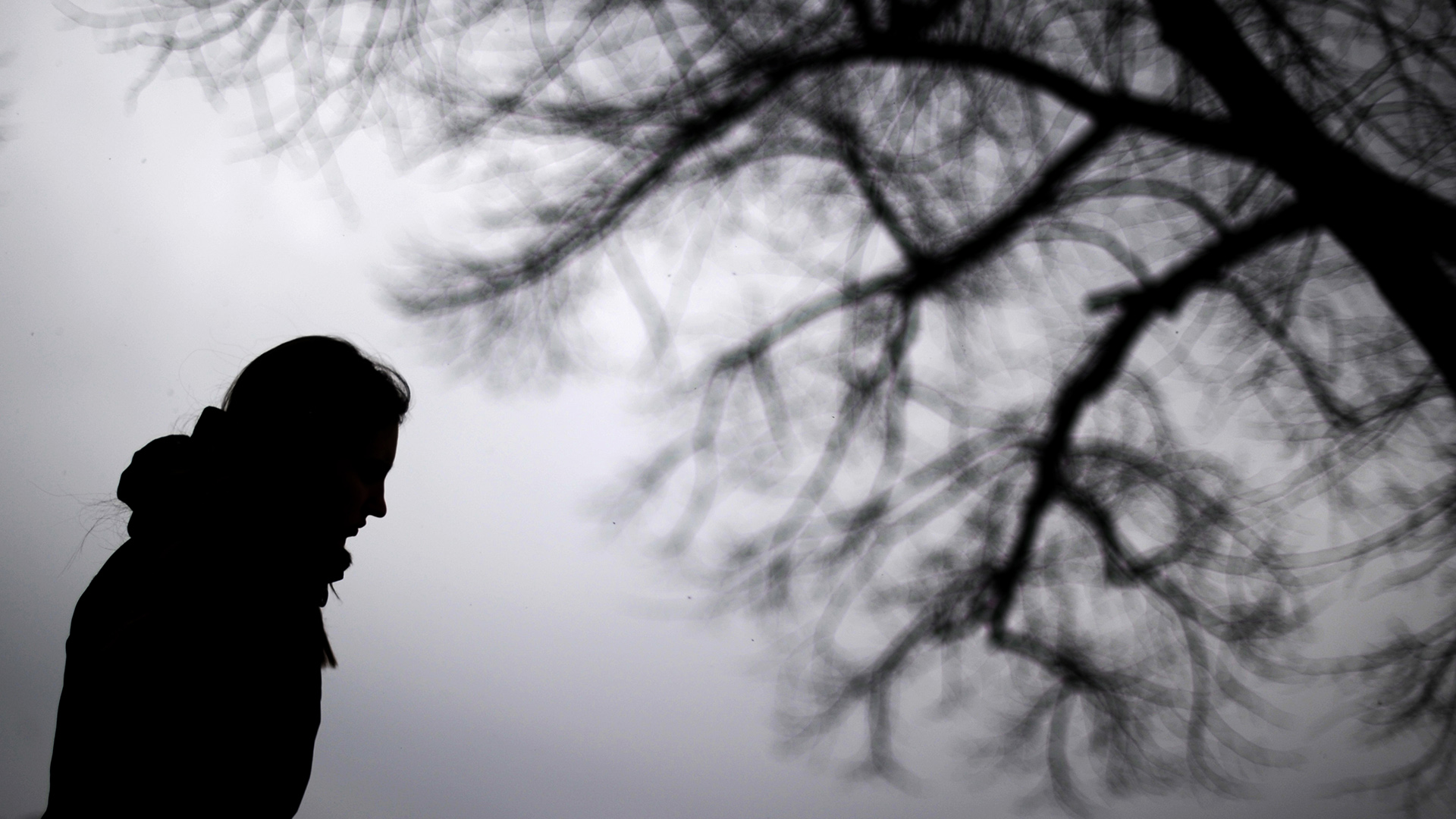 Eine Frau geht bei grauem Himmel in der kalten Jahreszeit spazieren. 