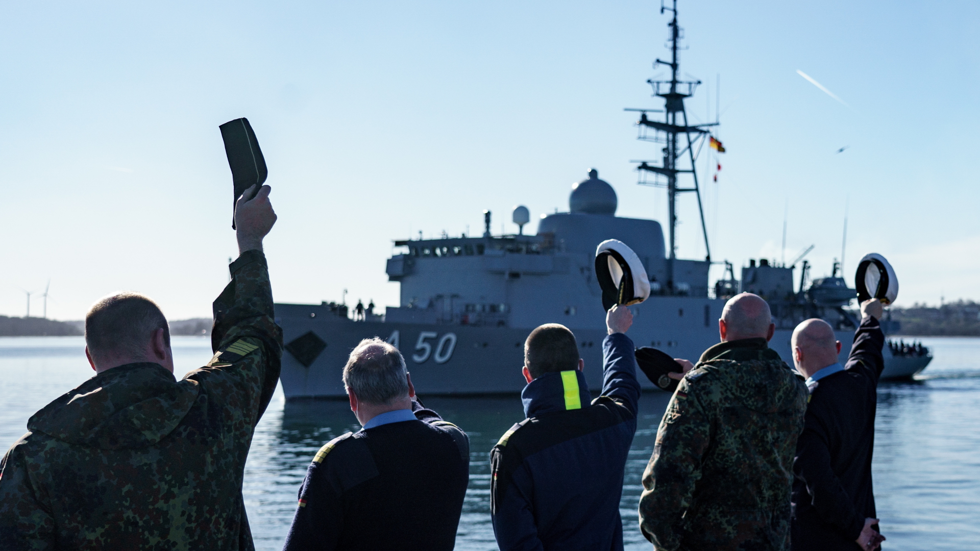Marinesoldaten winken dem Flottendienstboot "Alster" zu, welches zur Verstärkung der NATO-Nordflanke aus dem Marinehafen ausläuft. | dpa