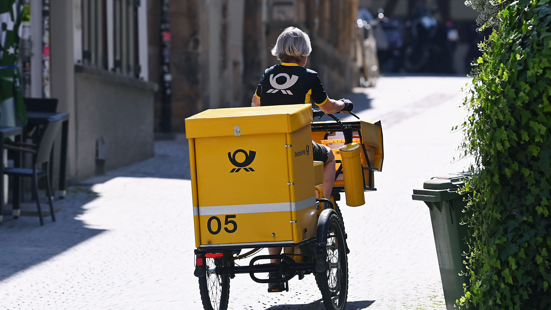 Eine Briefzustellerin ist mit dem Lastenrad in der Haaggasse in der Tuebinger Altstadt unterwegs.