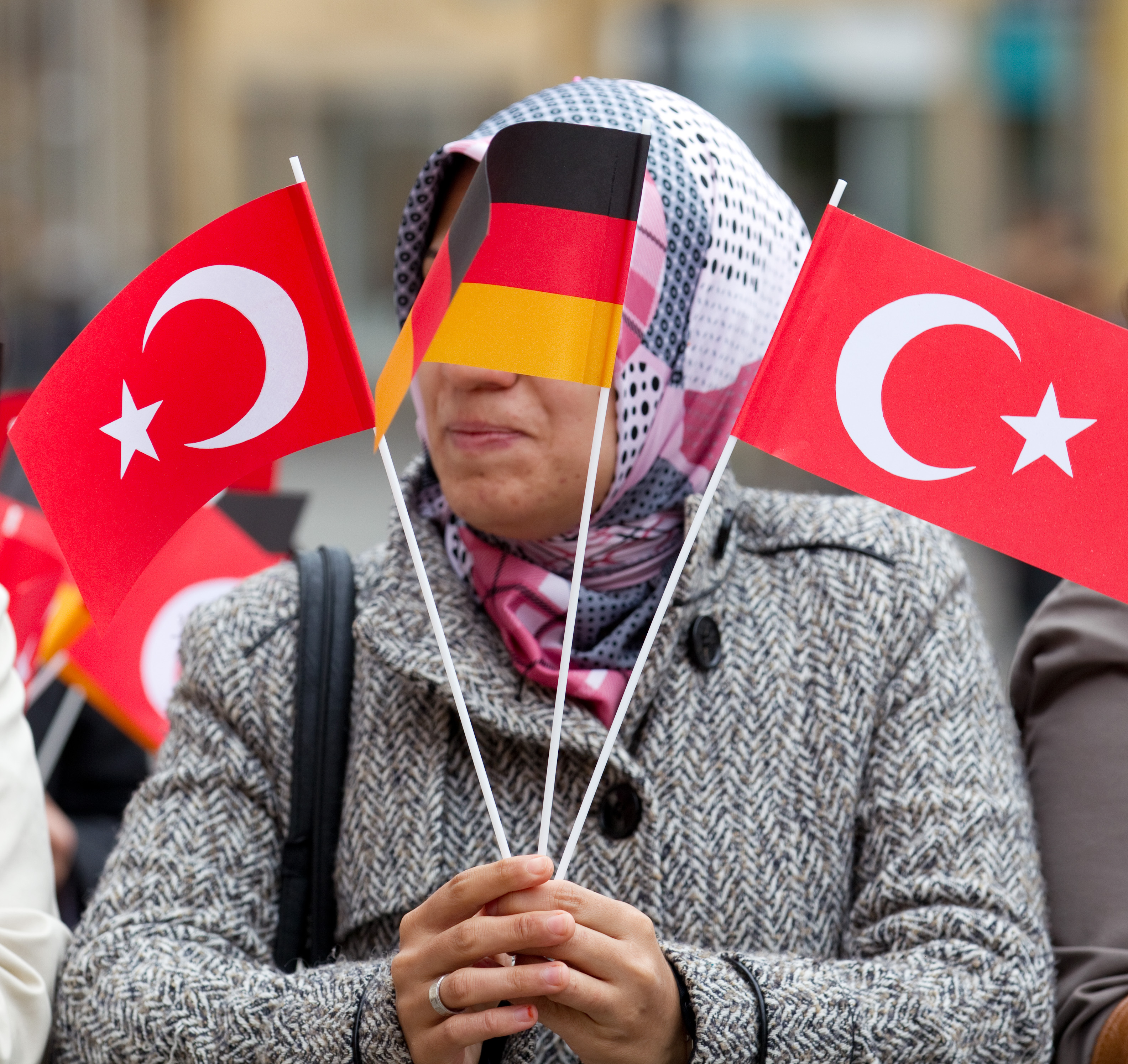 Auf einem Markt in Osnabrück hält eine Frau zwei türkische und eine deutsche Falgge in der Hand. | picture alliance / dpa