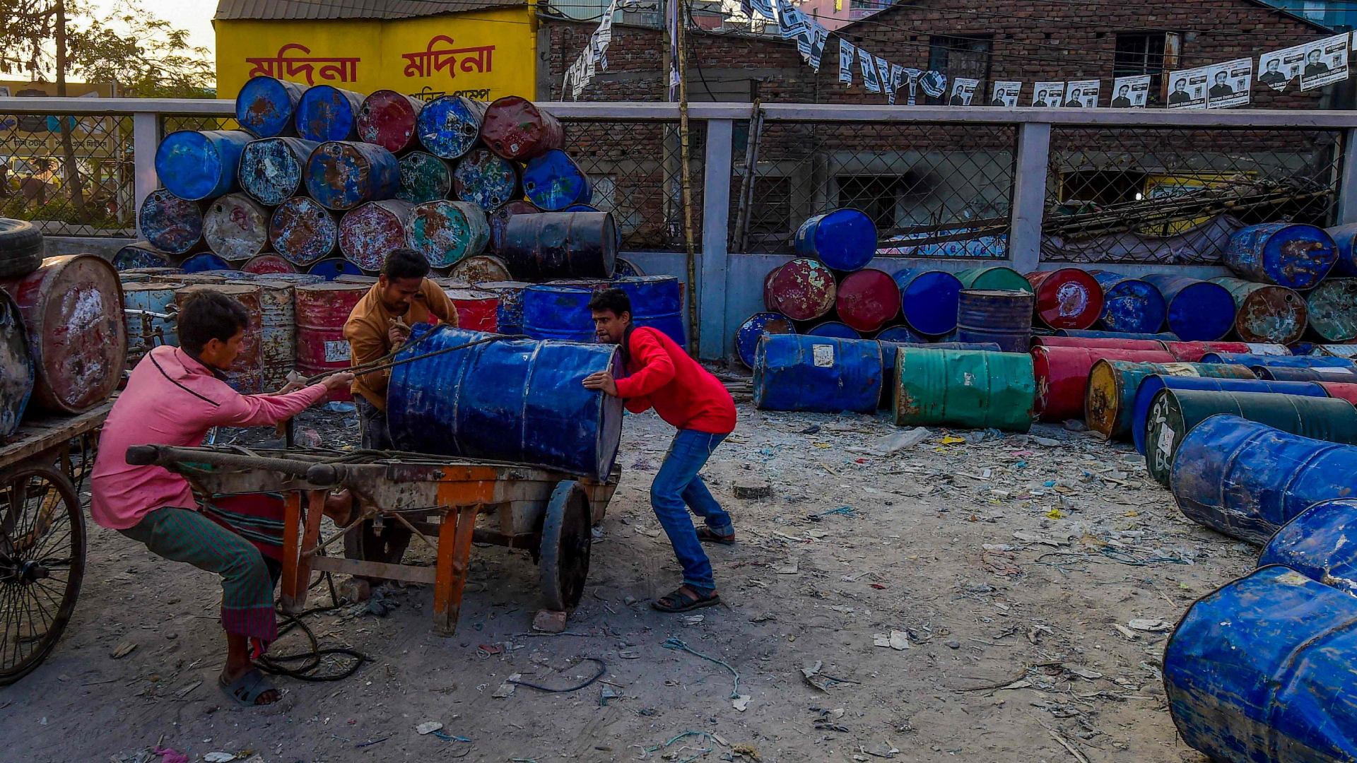 Männer in Dhaka laden Fässer auf einen Wagen | AFP