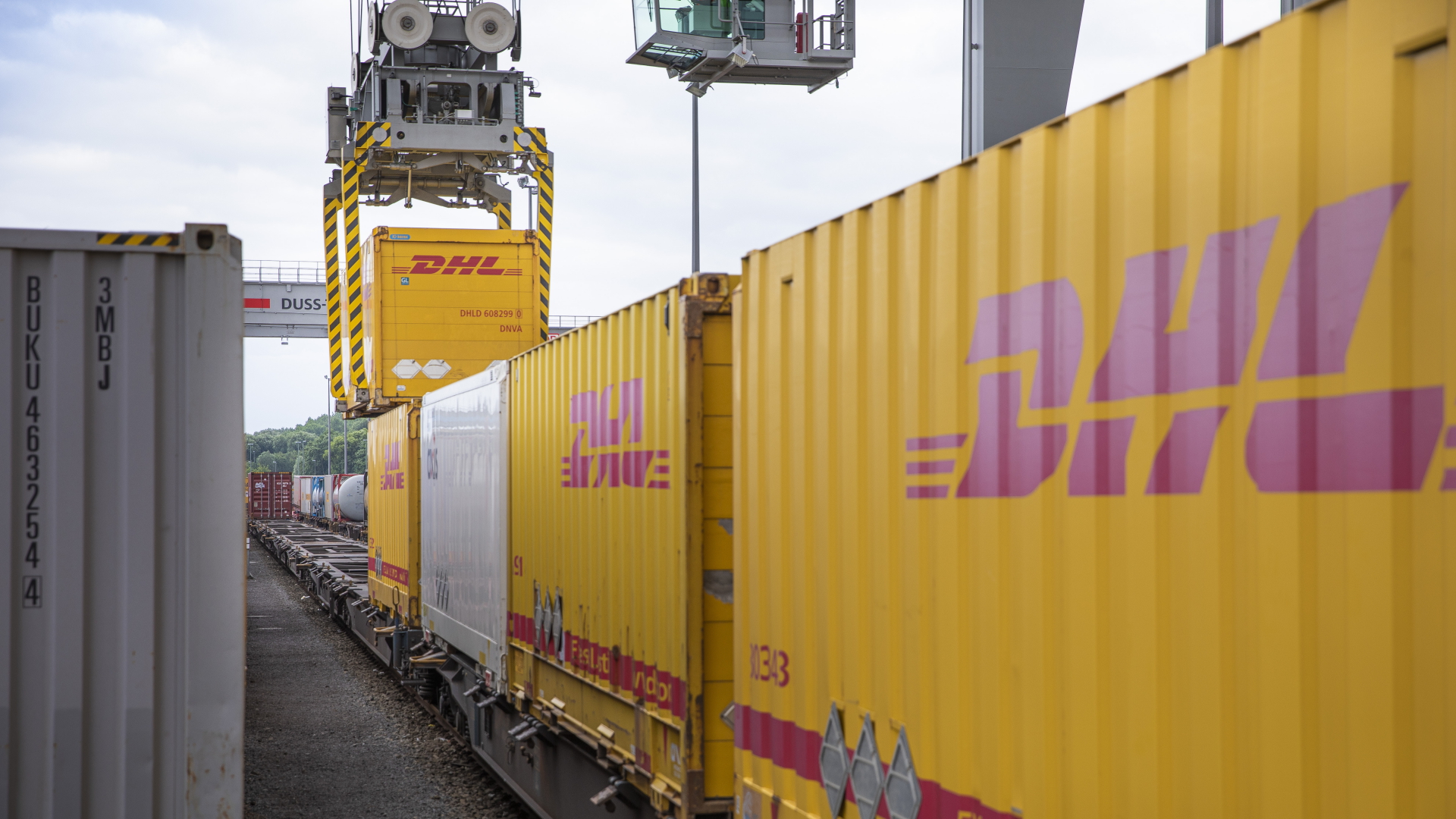 Ein Verladekran lädt einen DHL-Container auf einen Güterwaggon | dpa