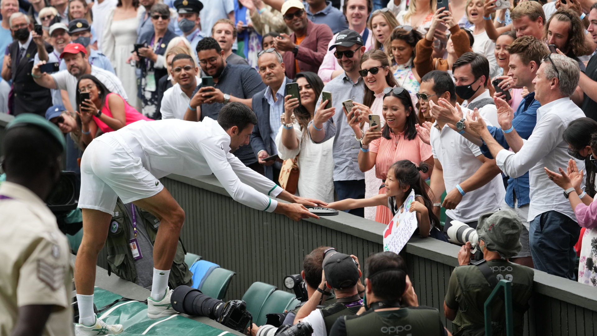 Novak Djokovic schenkt einem jungen Fan nach seinem Sieg in Wimbledon seinen Tennisschläger. | AP