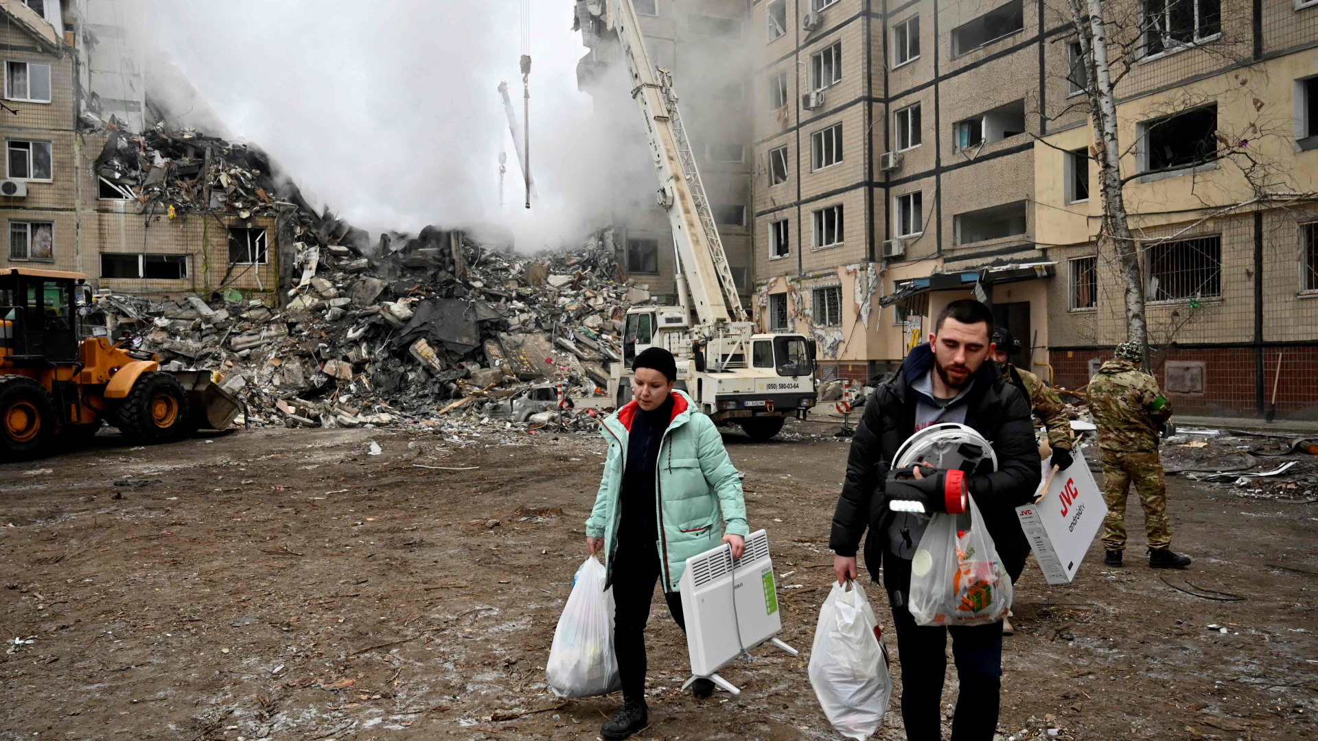 Menschen vor einem zerstörten Wohngebäude in Dnipro | AFP