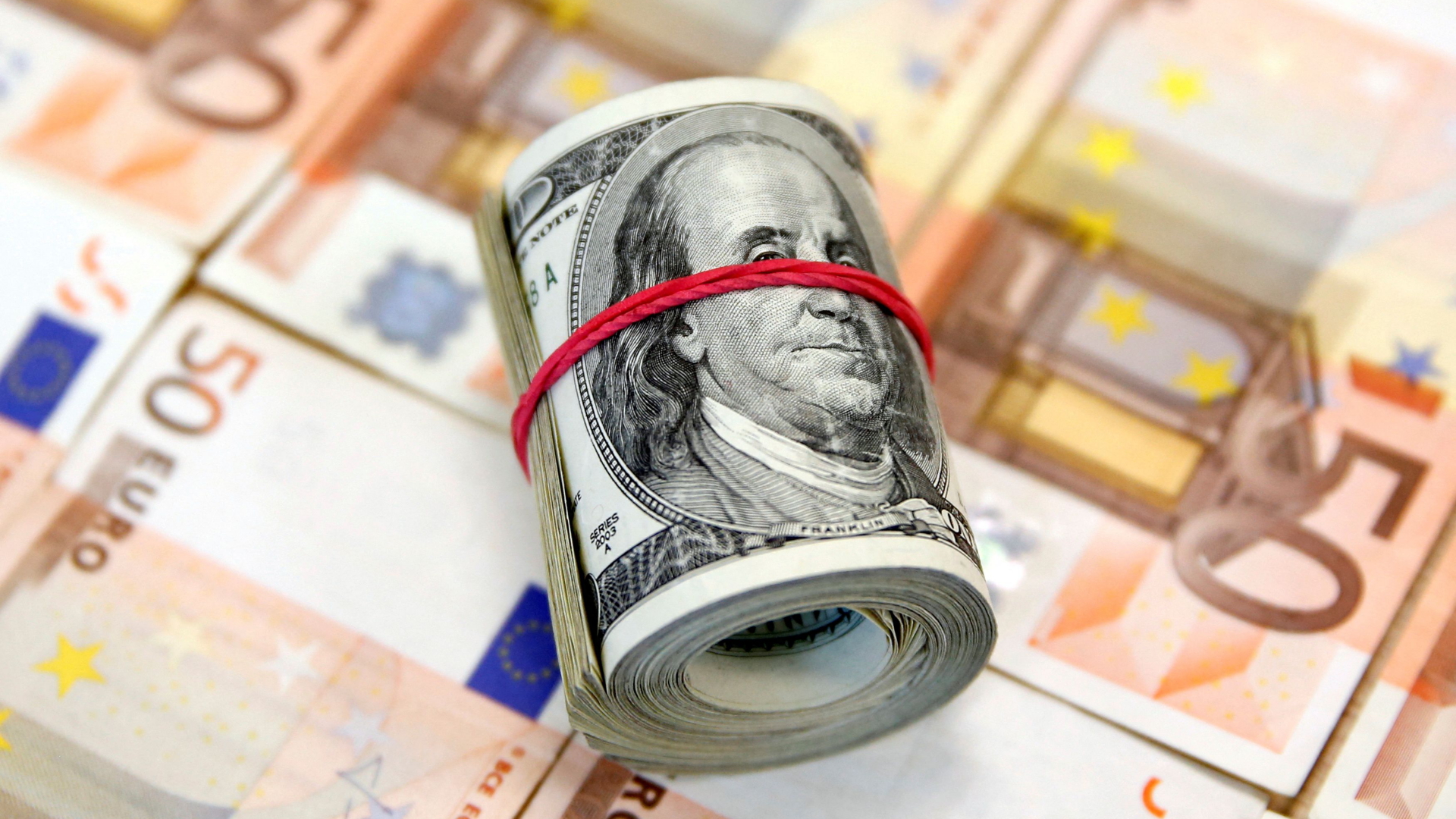 Gerolltes Bündel mit Dollar-Banknoten liegt auf 50-Euro-Geldscheinen | REUTERS