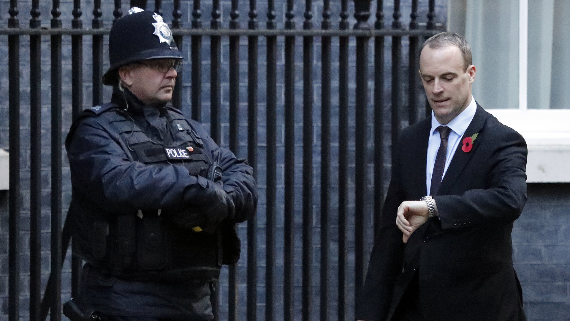 Brexit-Minister Dominic Raab kommt an der 10 Downing Street an und blickt neben einem Polizisten auf seine Uhr. | Bildquelle: AP