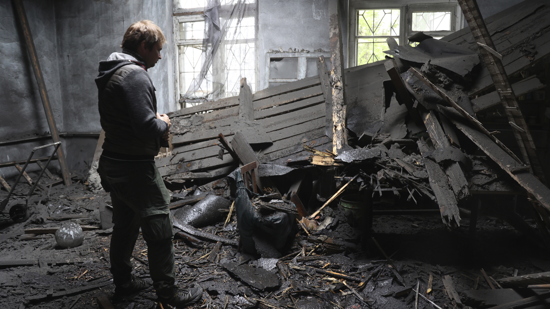 Ein Mensch steht inmitten der Trümmer eines zerstörten Hauses